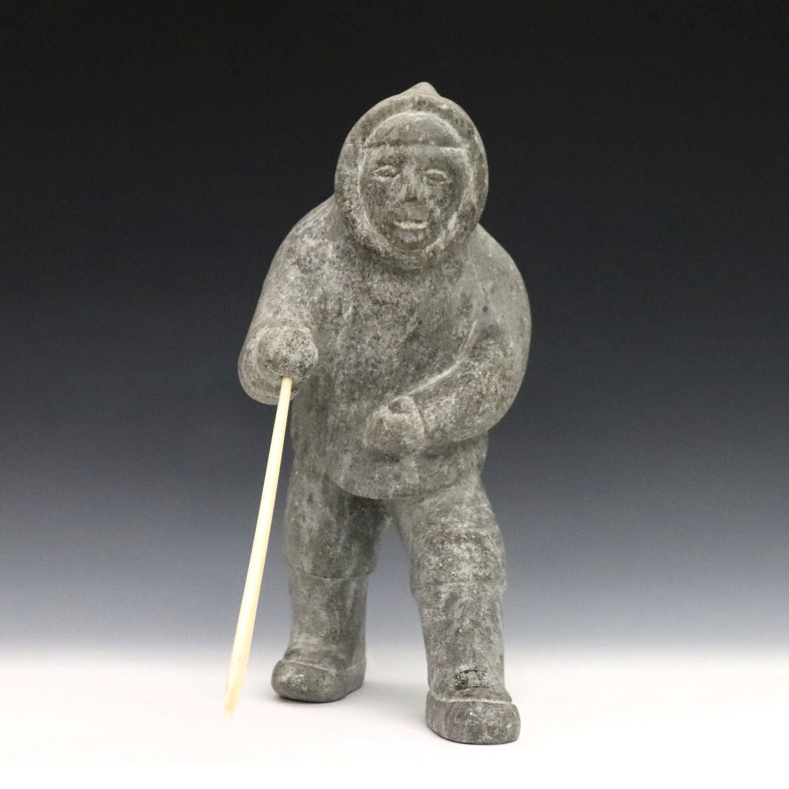 Inuit Carved Stone Hunter: A 20th century Inuit carved stone figure of a hunter with polished bone spear. Minor wear. 12" high. ESTIMATE $300-500