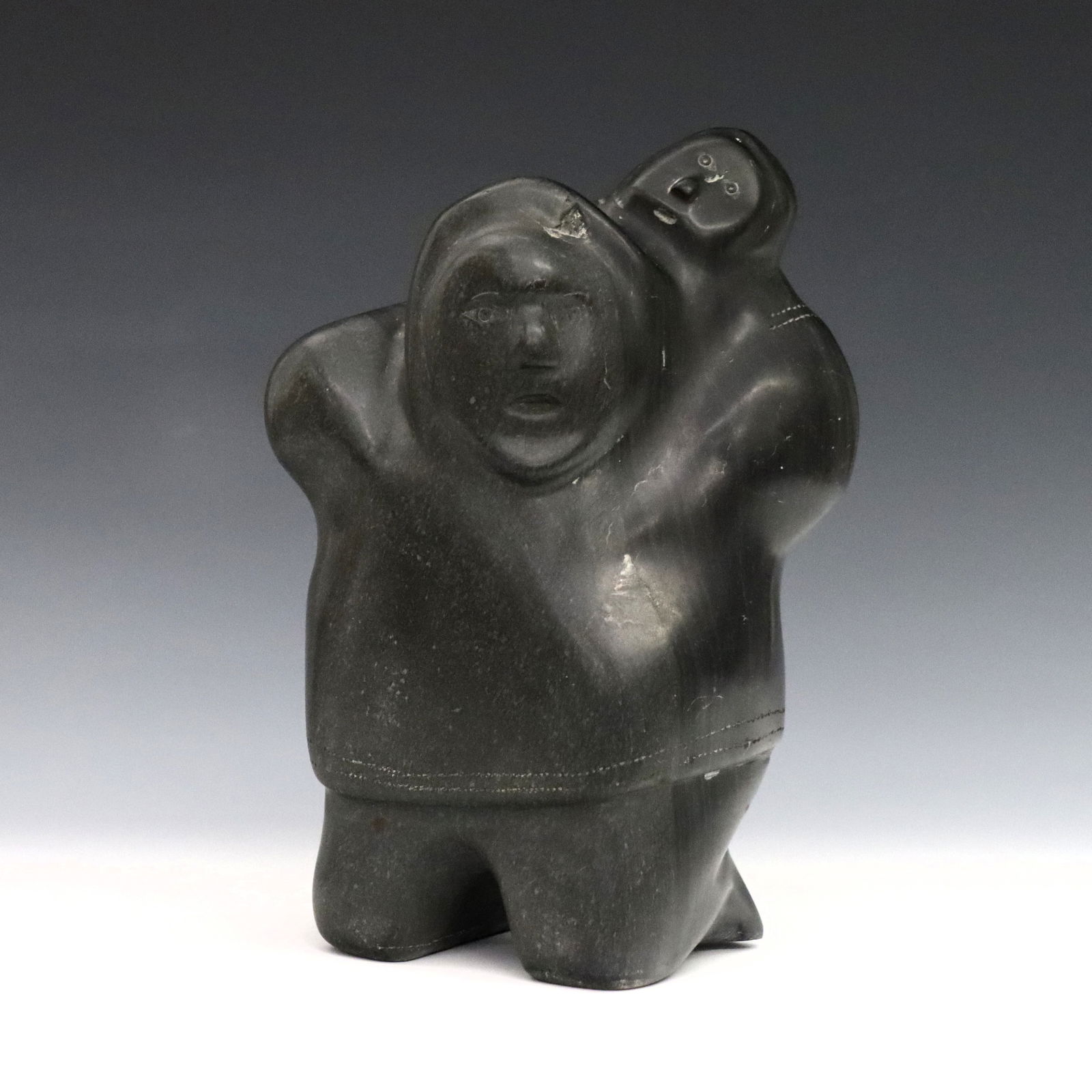 J. Emiqutailaq Inuit Stone Mother & Child: Joe Emiqutailaq, Inuit (Belcher Islands), b. 1918. A 20th century carved stone figure of a mother with a child at her back. Signed in syllabics with "E9-85" at underside. Minor wear. 7 3/4" high. ESTI