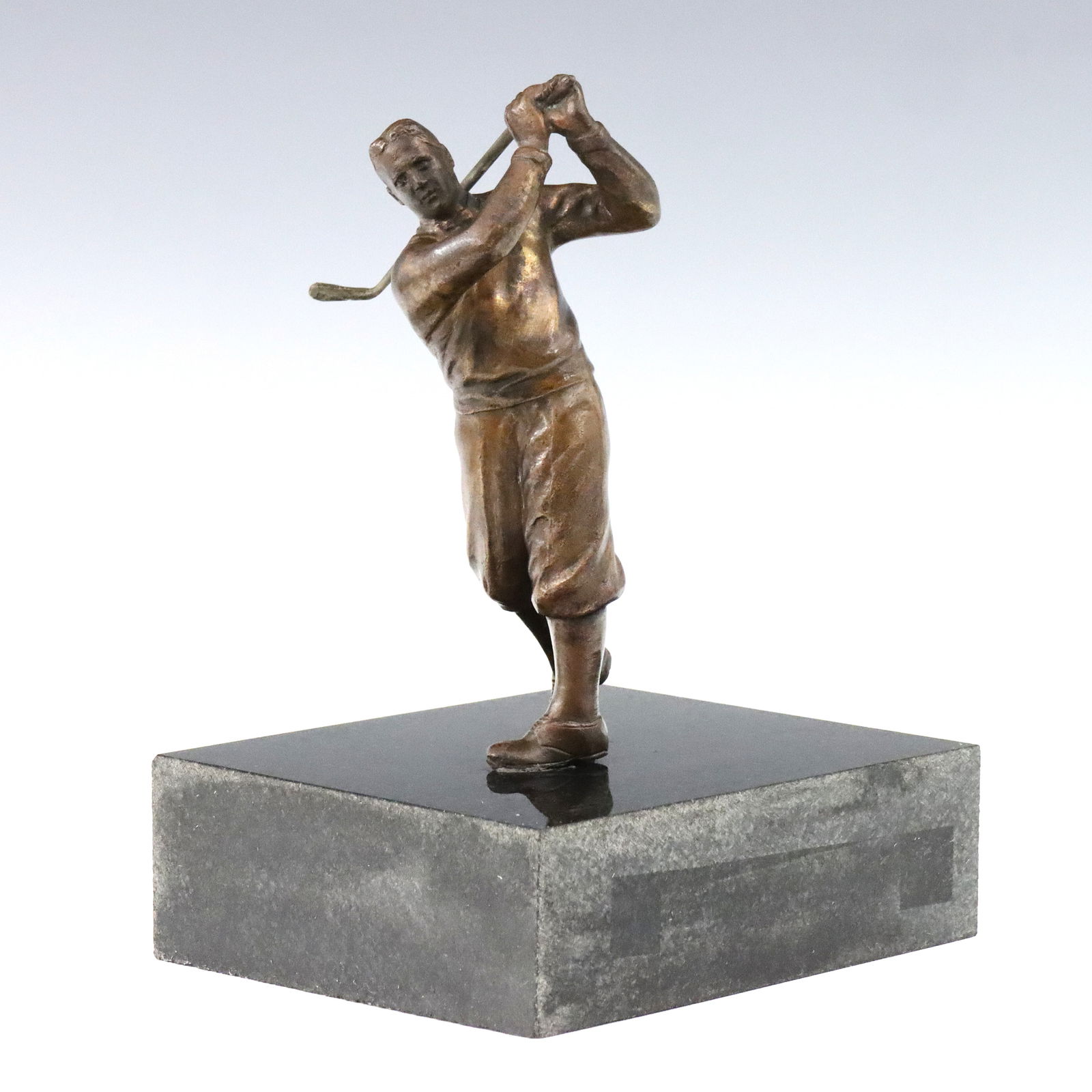 Bronze Figure of Bobby Jones: A 20th century Bronze figure of Bobby Jones. Depicts the golfer mid swing, presented on a Black Marble base. Minor wear to patina, discoloration at base. Figure is 6 1/2" high, 9" high overall. ESTIMA