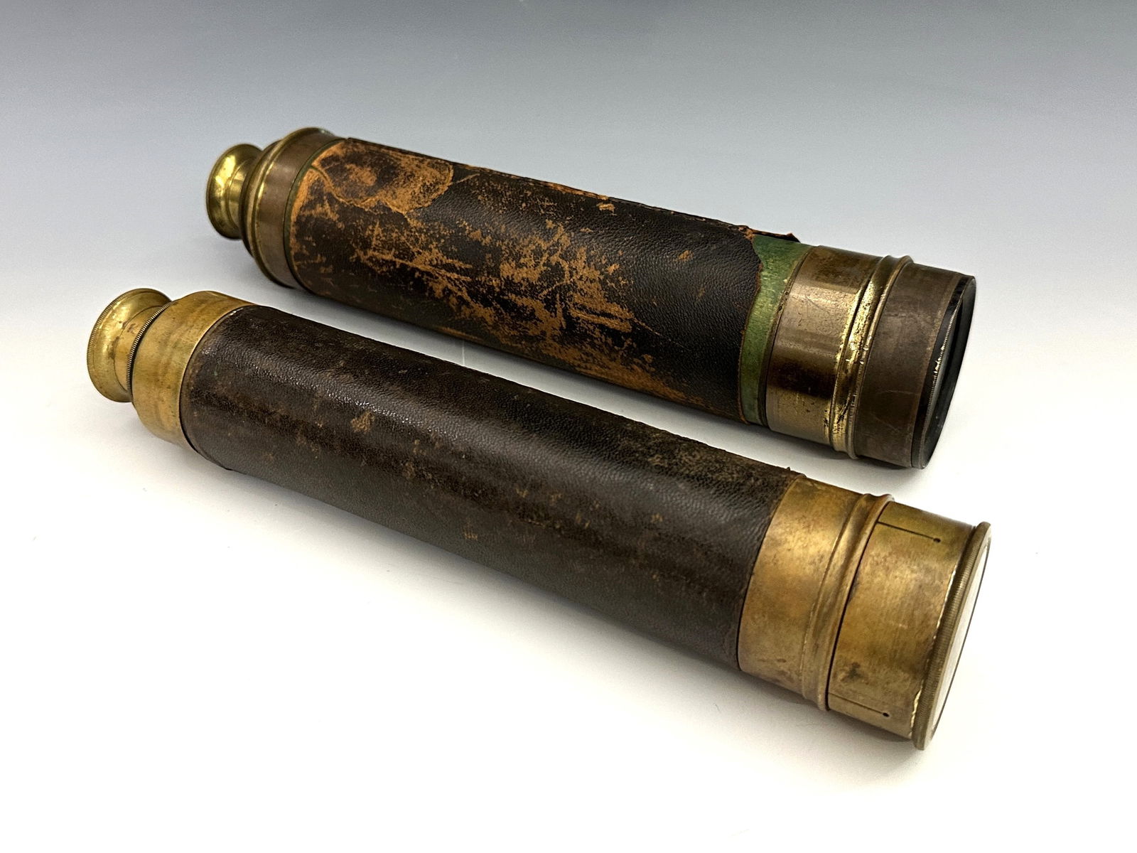 2 Brass Telescopes: Two 19th century Brass telescopes, one three-draw and the other four-draw. Leather covered barrels with 1 3/4" and 2" objective lenses, lift off and sliding Brass lens covers. Some wear to patina and