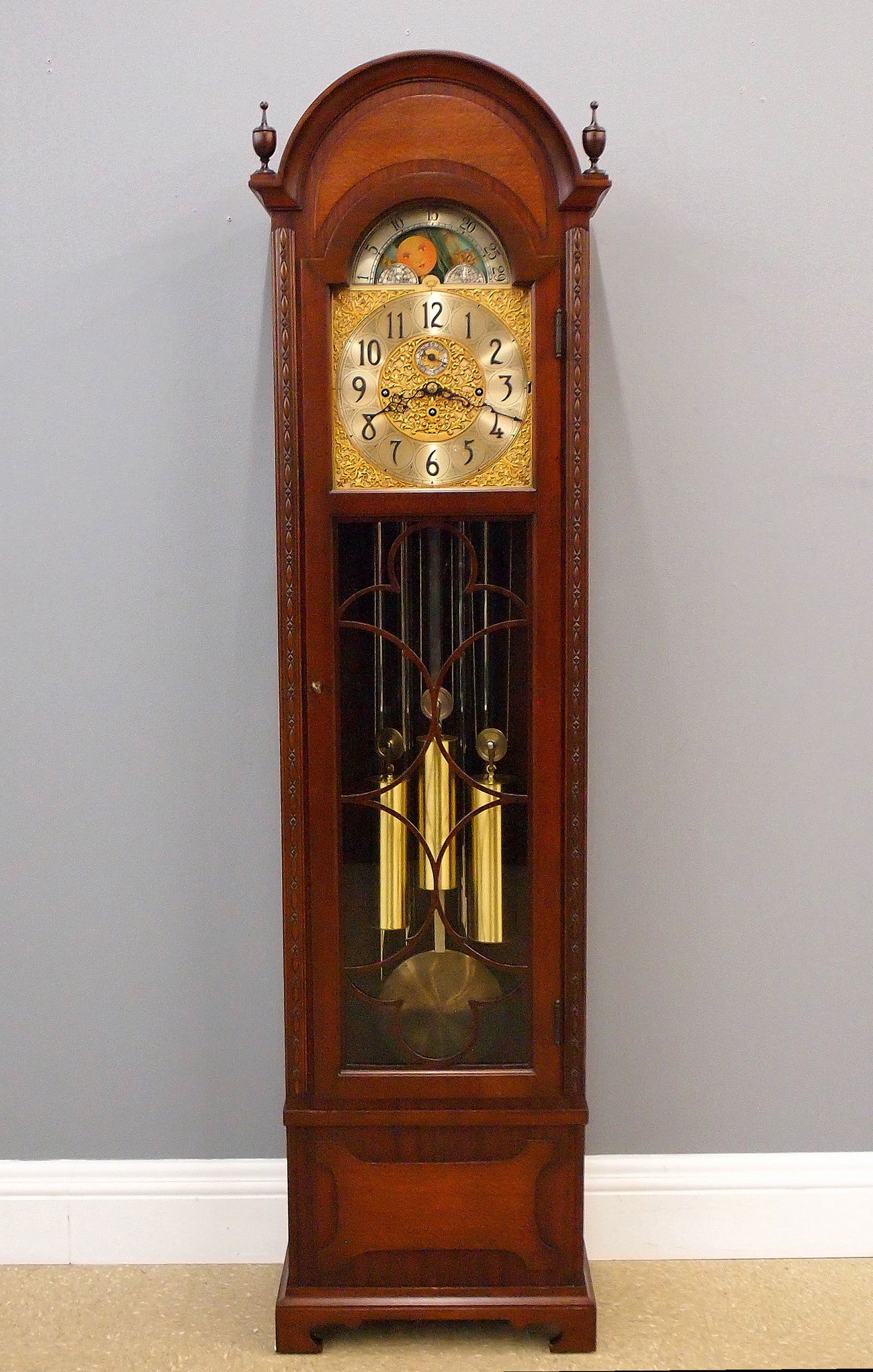 Herschede Grandfather Clock: A 1950's Herschede Hall Clock. 8-day weight driven time and strike movement with quarter hour Westminster chiming on five tubes, Brass filigree dial with upper moon phase and Roman numerals, serial #5
