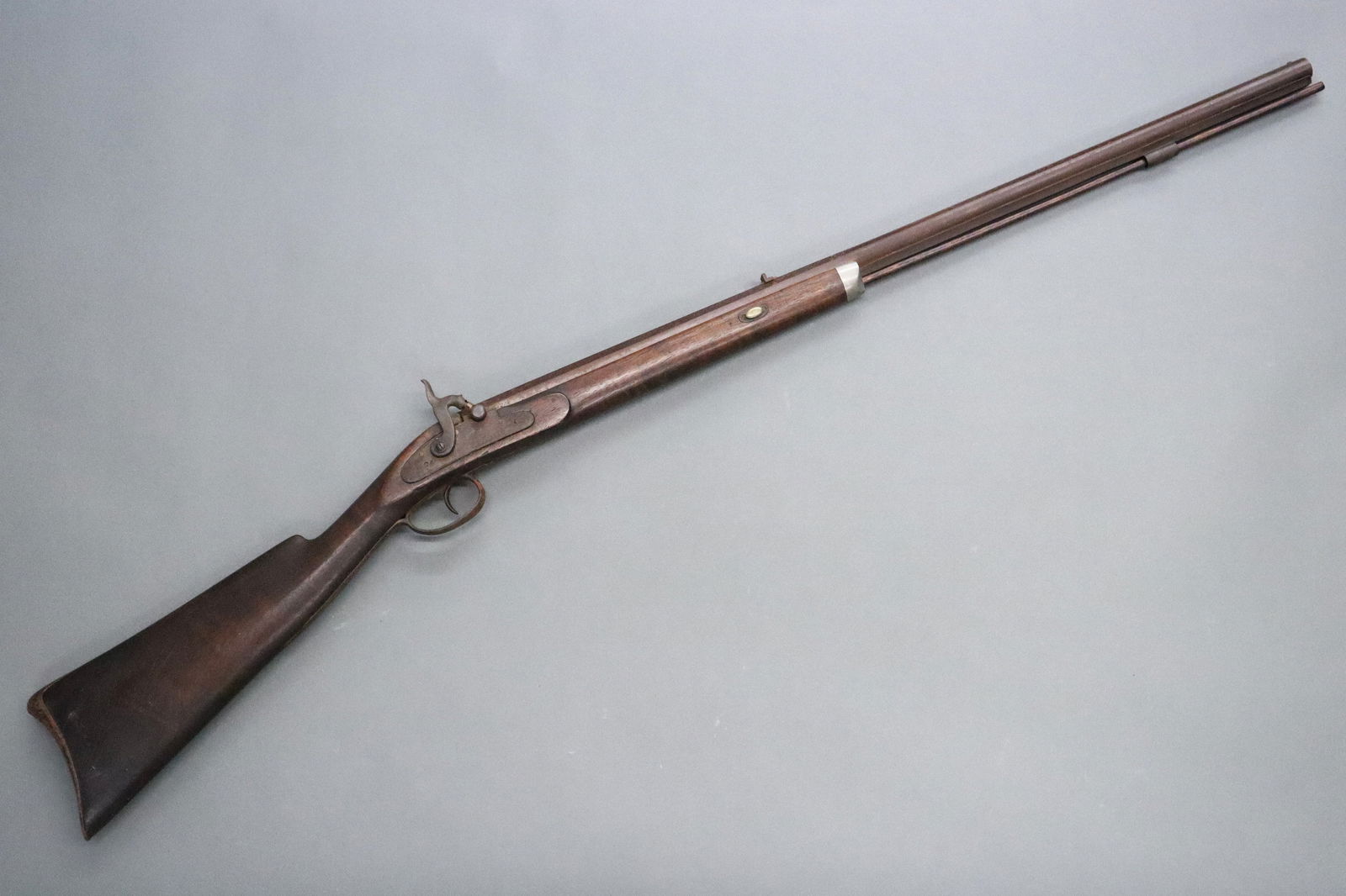 N. Ashmore Rifle: A 19th century N. Ashmore muzzle loading rifle. .45 Caliber with 30" octagonal barrel and Walnut stock. Marked "N. Ashmore" with engraved designs at lock plate. Oxidation and wear, small chips to stoc