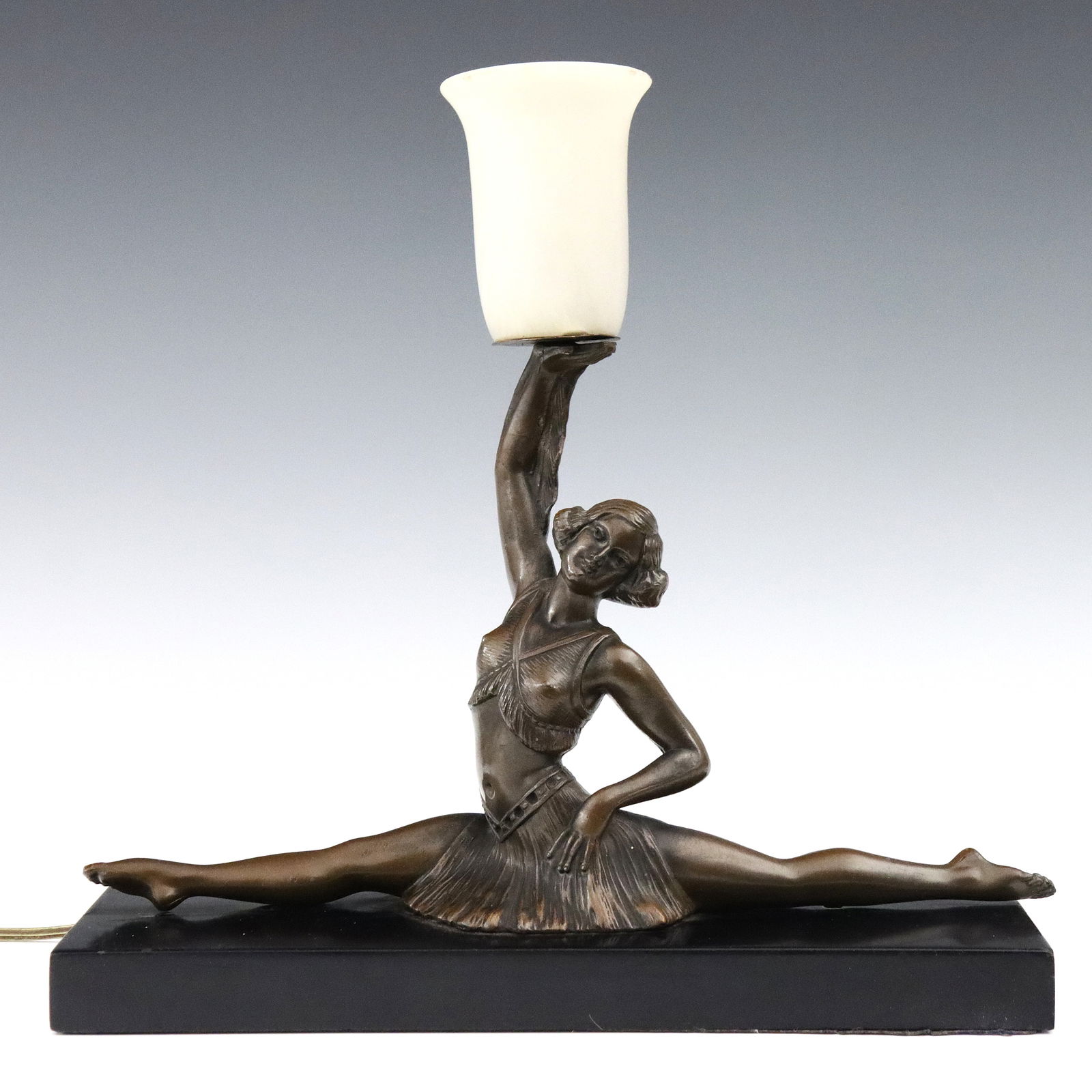 Art Deco Lamp: An early 20th century Art Deco Period figural lamp. Patinated spelter figure of a female performer doing the splits on a polished slate base with mottled White glass shade. Shade with some chips to ed