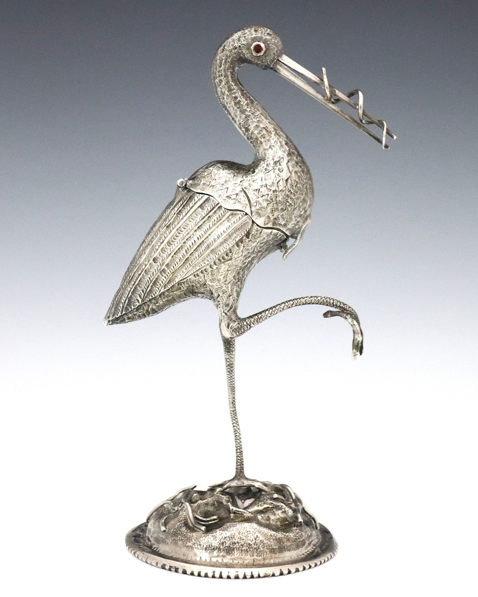 Dutch Sterling Stork Spice Box: A turn of the century Dutch Sterling Stork spice box. Figural Stork form box with Red gemstone eyes, posed standing with one leg raised and a serpent in its beak. Hinged body opens to reveal a compart