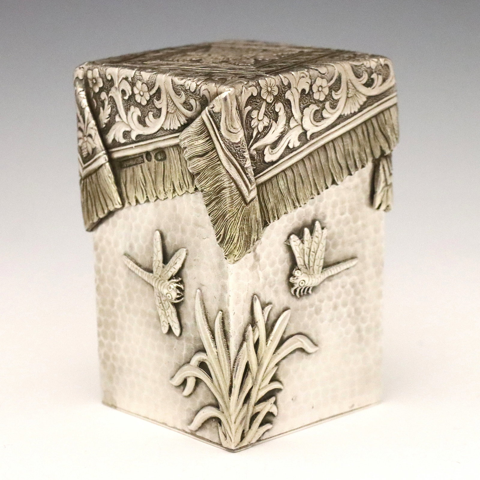 Russian Silver Covered Box: An early 20th century Russian .875 Silver covered box. Rectangular form with trompe l'oeil cover depicting a draped textile over a hand hammered bottom with cast Dragonflies and foliage. Double marked