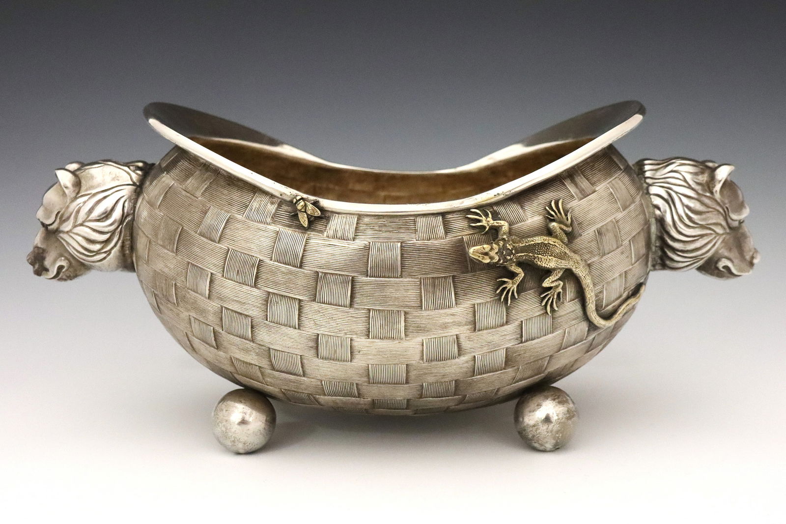 Russian Silver Center Bowl: An early 20th century Russian .875 Silver footed center bowl. Oval form with two Bear head handles and trompe l'oeil basket weave exterior decorated with a cast Lizard hunting a fly, raised on four ba