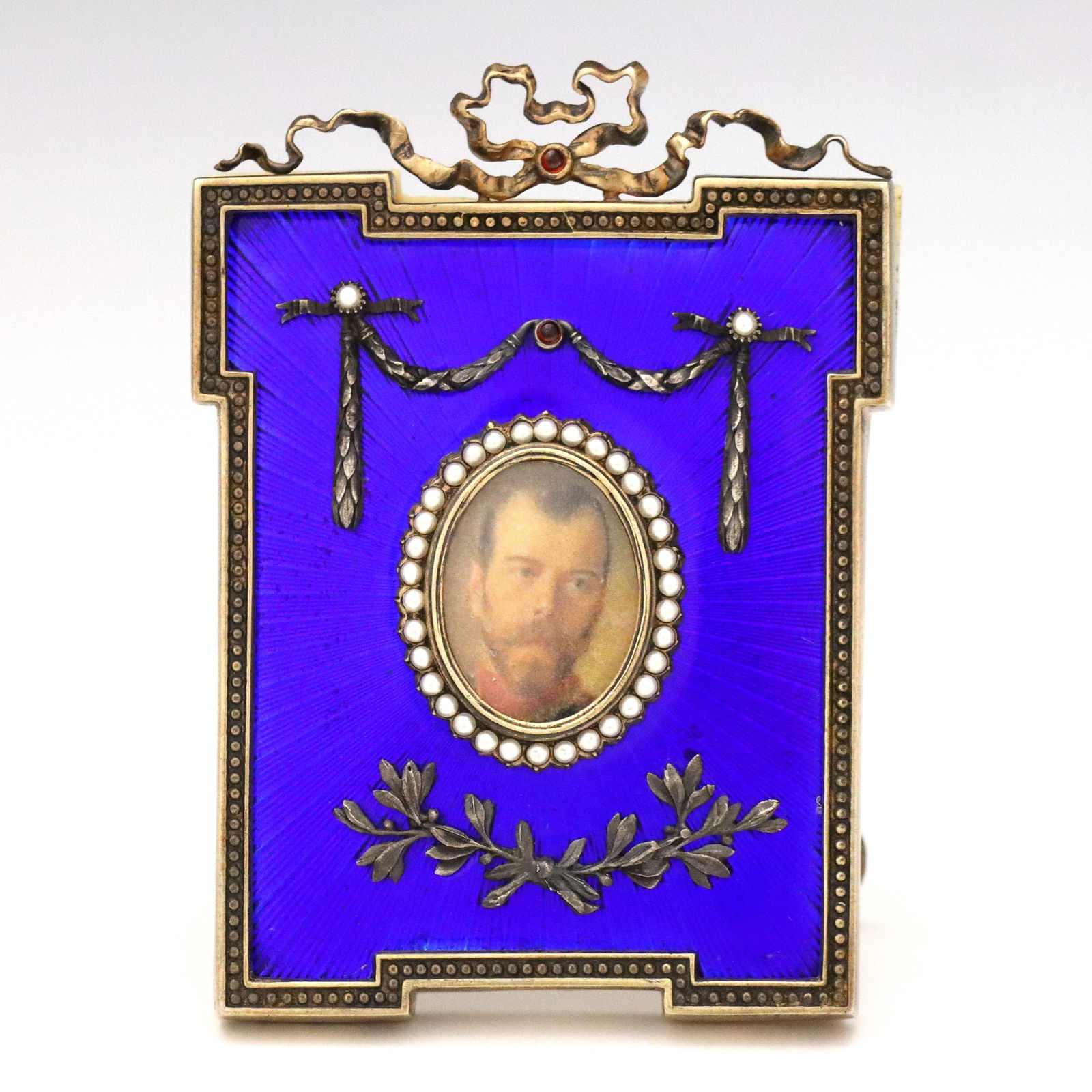 Russian Enameled Silver Miniature Frame: An early 20th century Russian miniature Silver frame with enameled Guilloche decoration. Rectangular Gilded Silver frame with Blue enamel decoration and cast garlands with Pearl and gemstone accents.