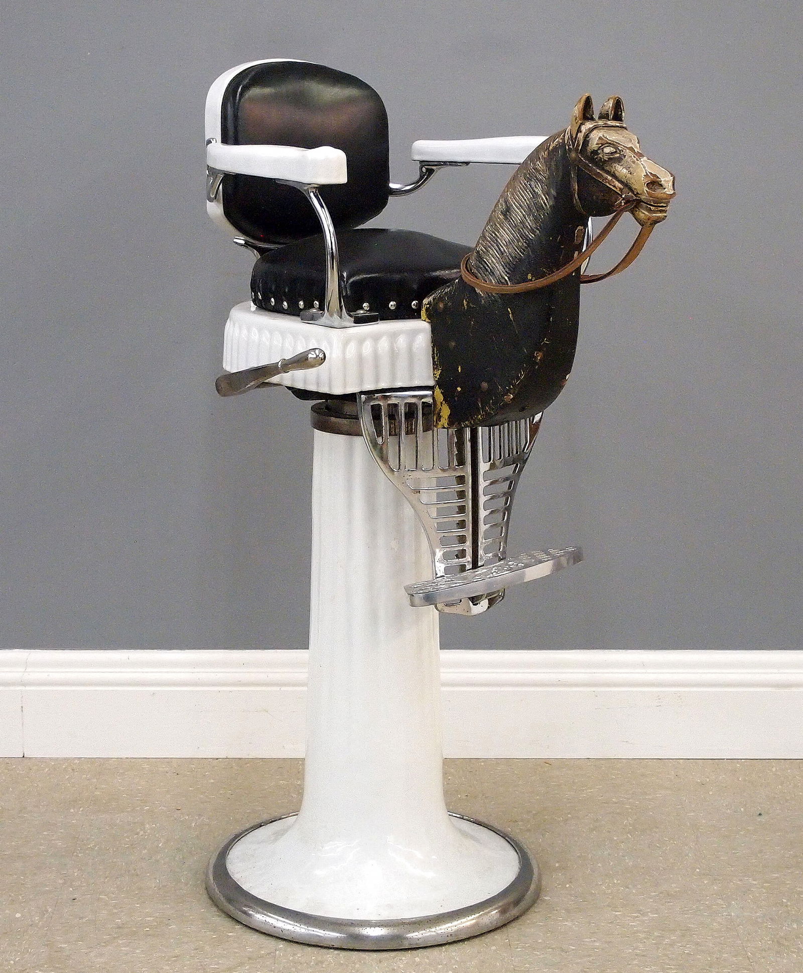 Koken Child's Barber Chair With Pony: A turn of the century child's barber chair with Pony. Cast Iron construction with White porcelain finish, features a hydraulic child's size chair with upholstered back and seat, carved wooden pony