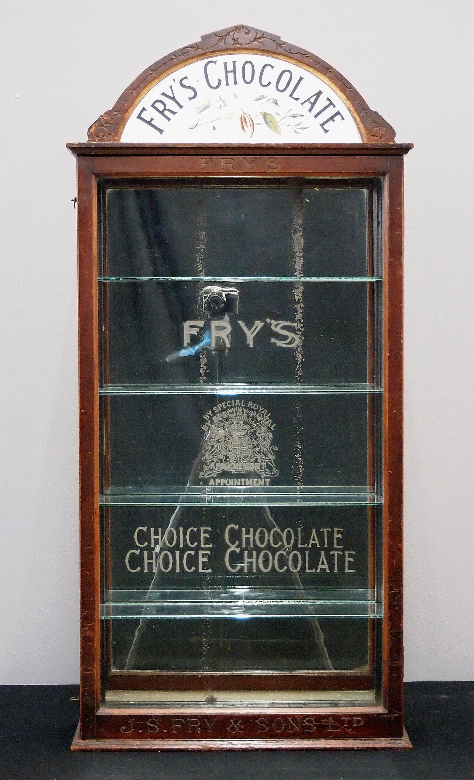 Fry's Chocolates Store Display Cabinet: A turn of the century Fry's Chocolates wall hanging store display cabinet. Walnut construction features an arched crown with porcelain advertising panel reading "Fry's Chocolate" over a single long gl