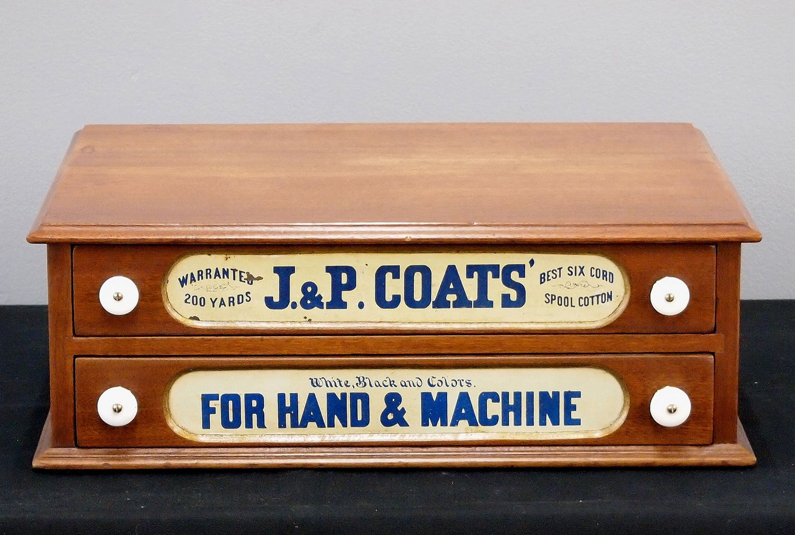 J. P. Coats Thread Cabinet: A turn of the century J. P. Coats counter top thread cabinet. Walnut construction features two drawers with painted labels and porcelain knobs. Refinished with minor wear. 19 x 15 1/2 x 7" high
