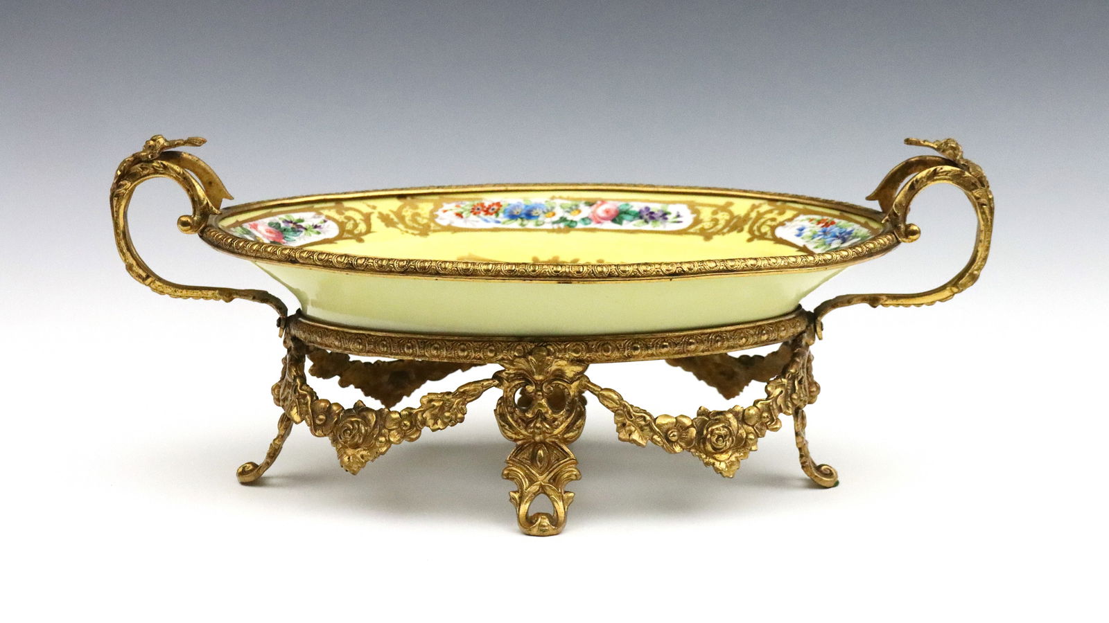 French Sevres Style Center Bowl: A late 19th century French Sevres style mounted porcelain center bowl. Oval porcelain dish with Romantic scenic decoration and floral borders on a Yellow ground, mounted on a Gilded Bronze frame with