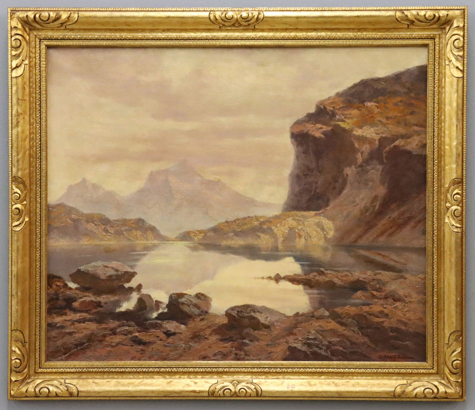 J.E. Califano Mountainscape: John Edmund Califano, Italian/American, 1862-1946. An oil on canvas landscape depicting a serene lake surrounded by majestic mountains in tones of Light Pink and Purple, Browns, and Whites. Signed