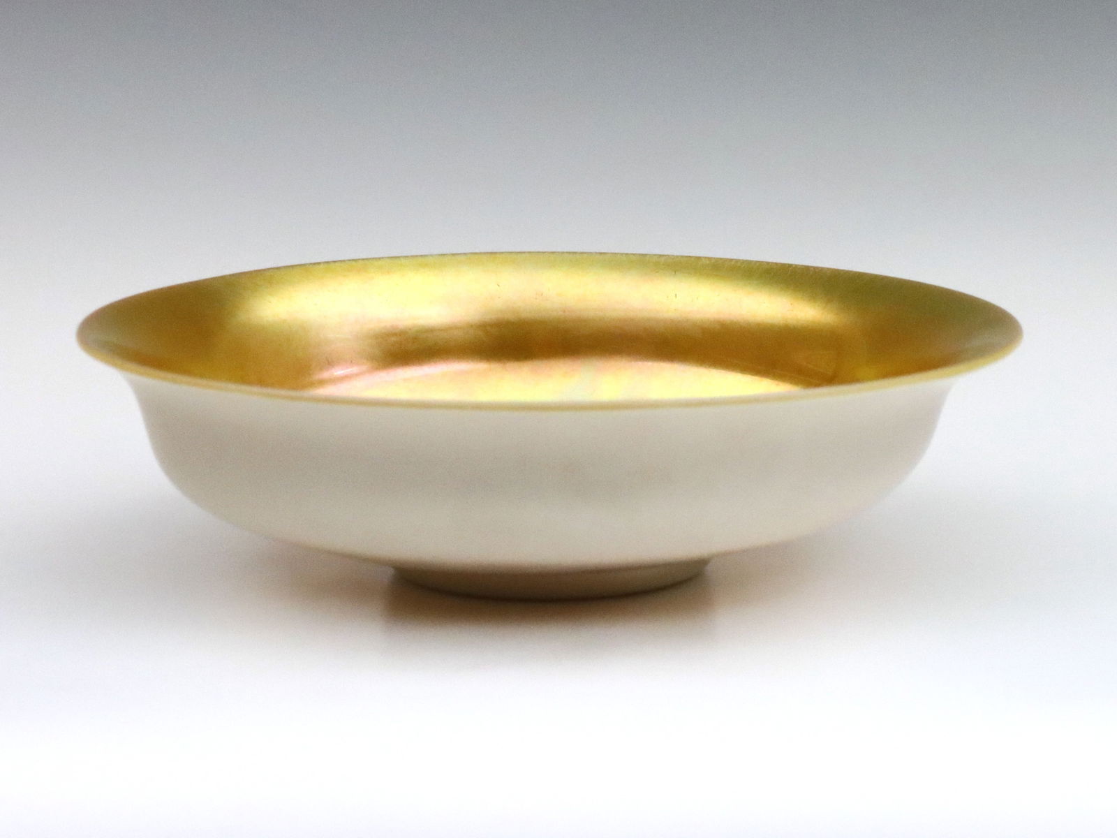Steuben Aurene & Calcite Glass Bowl: An early 20th century Steuben Art Glass center bowl. Low footed form with flared rim, Gold Aurene interior and Calcite exterior. Unmarked. Minor surface wear, two small darkened spots in interior from