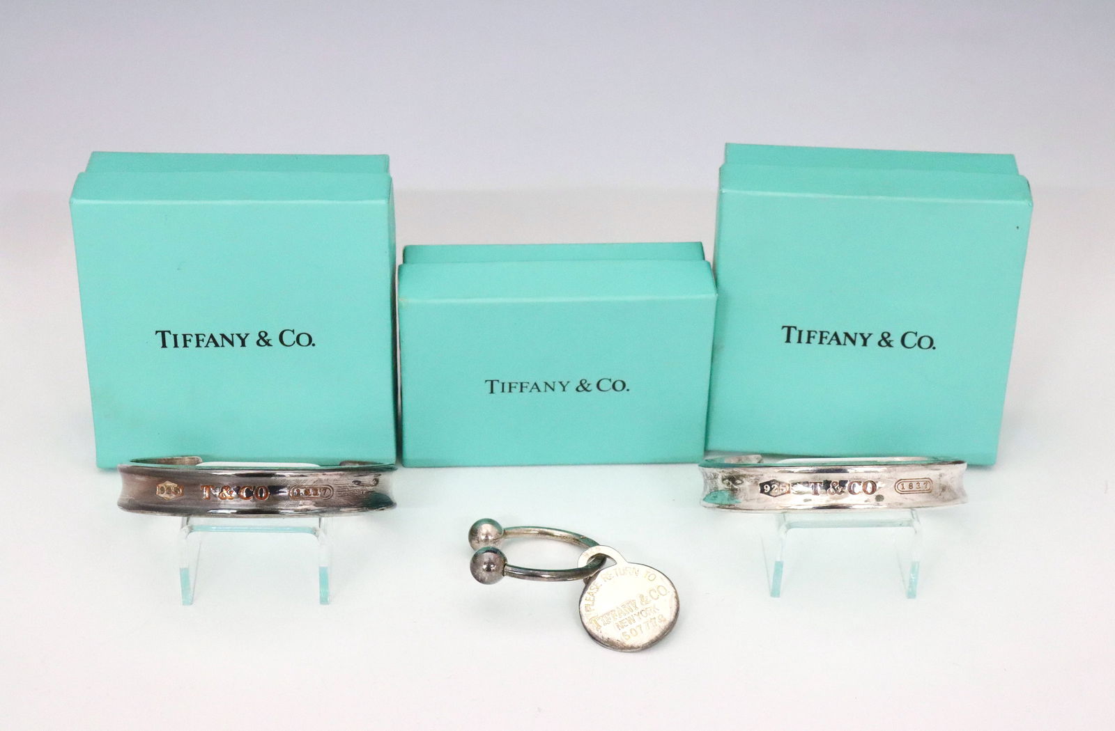 3 Tiffany Sterling Accessories: Three vintage Tiffany & Co. Sterling Silver accessories. Includes two 1997 cuff bracelets and a 2001 "Please Return to Tiffany" round tag key ring, all in the original boxes. Bracelets each double