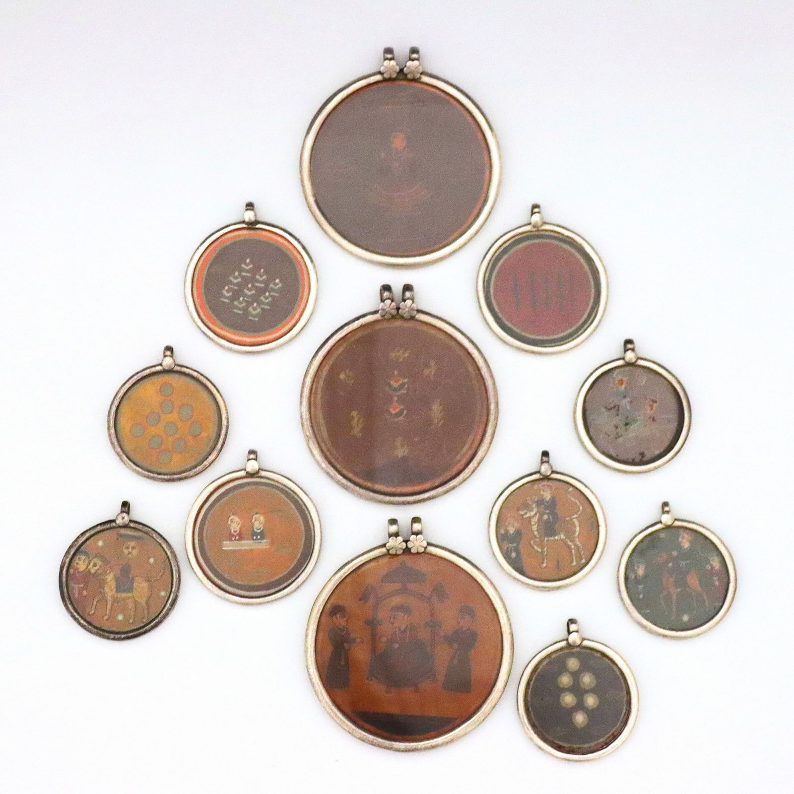 12 Indian Sterling Ganjifa Card Pendants: Twelve vintage Indian Ganjifa playing card pendants in Sterling Silver medallion frames. Features hand-painted polychrome Ganjifa playing cards with figural and geometric designs, framed under glass