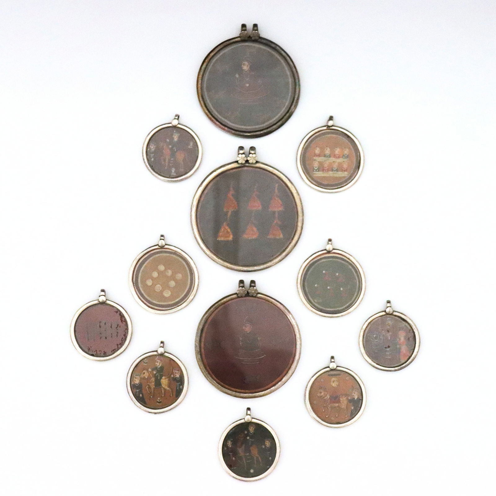 12 Indian Sterling Ganjifa Card Pendants: Twelve vintage Indian Ganjifa playing card pendants in Sterling Silver medallion frames. Features hand-painted polychrome Ganjifa playing cards with figural and geometric designs, framed under glass