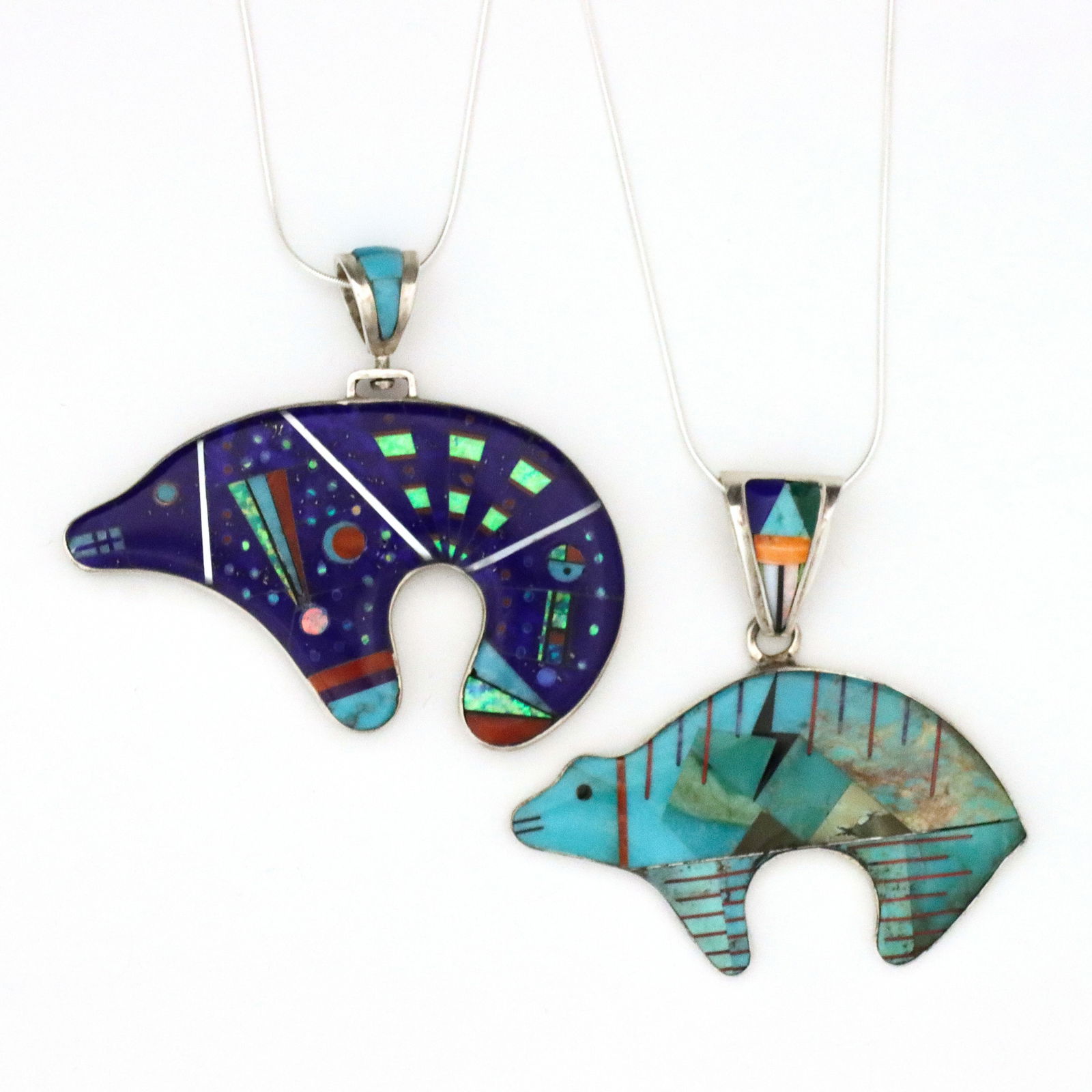 2 Native American Sterling Bear Necklaces: Two vintage Native American Sterling Bear pendant necklaces. Bear form pendants inlaid with Turquoise, Lapis Lazuli, Jet, Mother of Pearl, Coral and Opal. Larger Bear is reversible, one side predomina