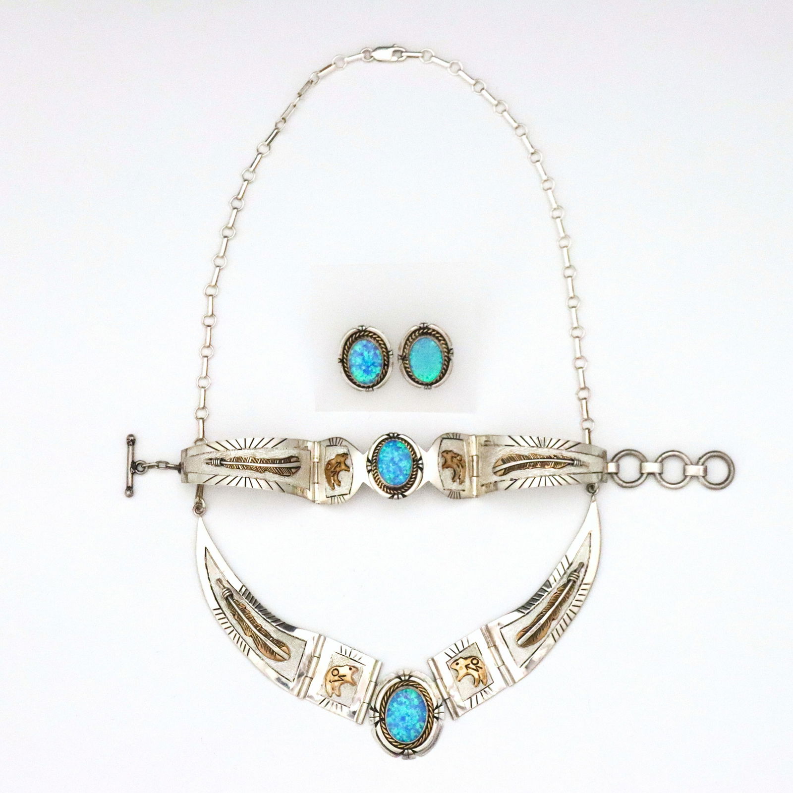 M. Toledo Navajo 3 pc Sterling & Opal Jewelry Set: A vintage three piece Navajo Sterling Silver and Opal jewelry set by Mary Toledo. Features hinged Sterling segments with central oval bezel set Blue Opal cabochons flanked by gold tone bear and feathe