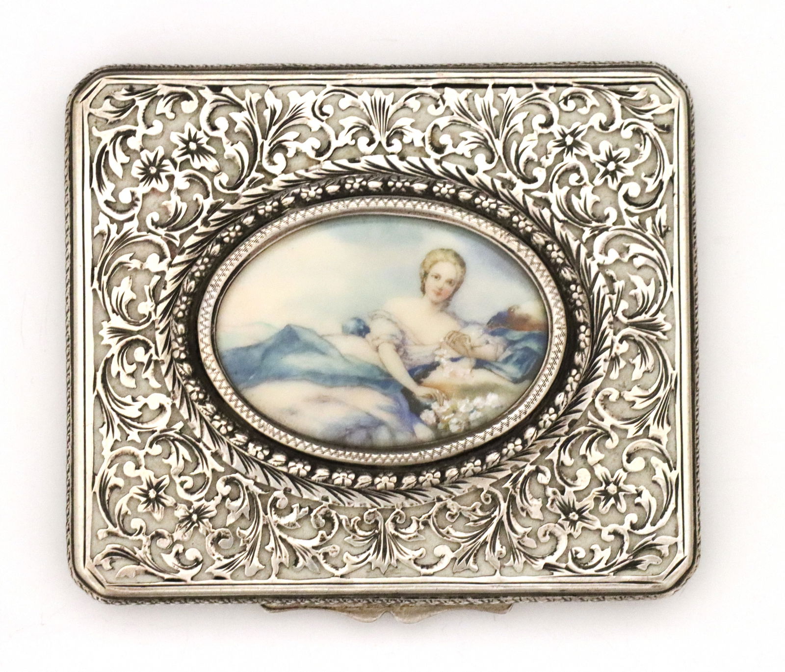 .800 Silver Portrait Compact: A turn of the century Continental .800 Silver compact with portrait insert. Rectangular form with hinged filigree lid featuring a hand-painted insert depicting a lounging woman, with engraved foliate