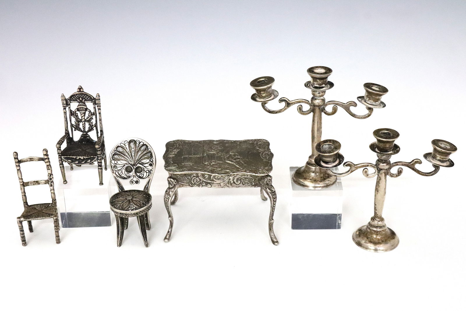 6 Silver Miniature Figures: Six 19th to 20th century Silver miniature figures. Includes a pair of Mexican Sterling candelabra, a Continental .800 Silver table with Romantic scenic decoration, two Dutch .835 Silver chairs, and a