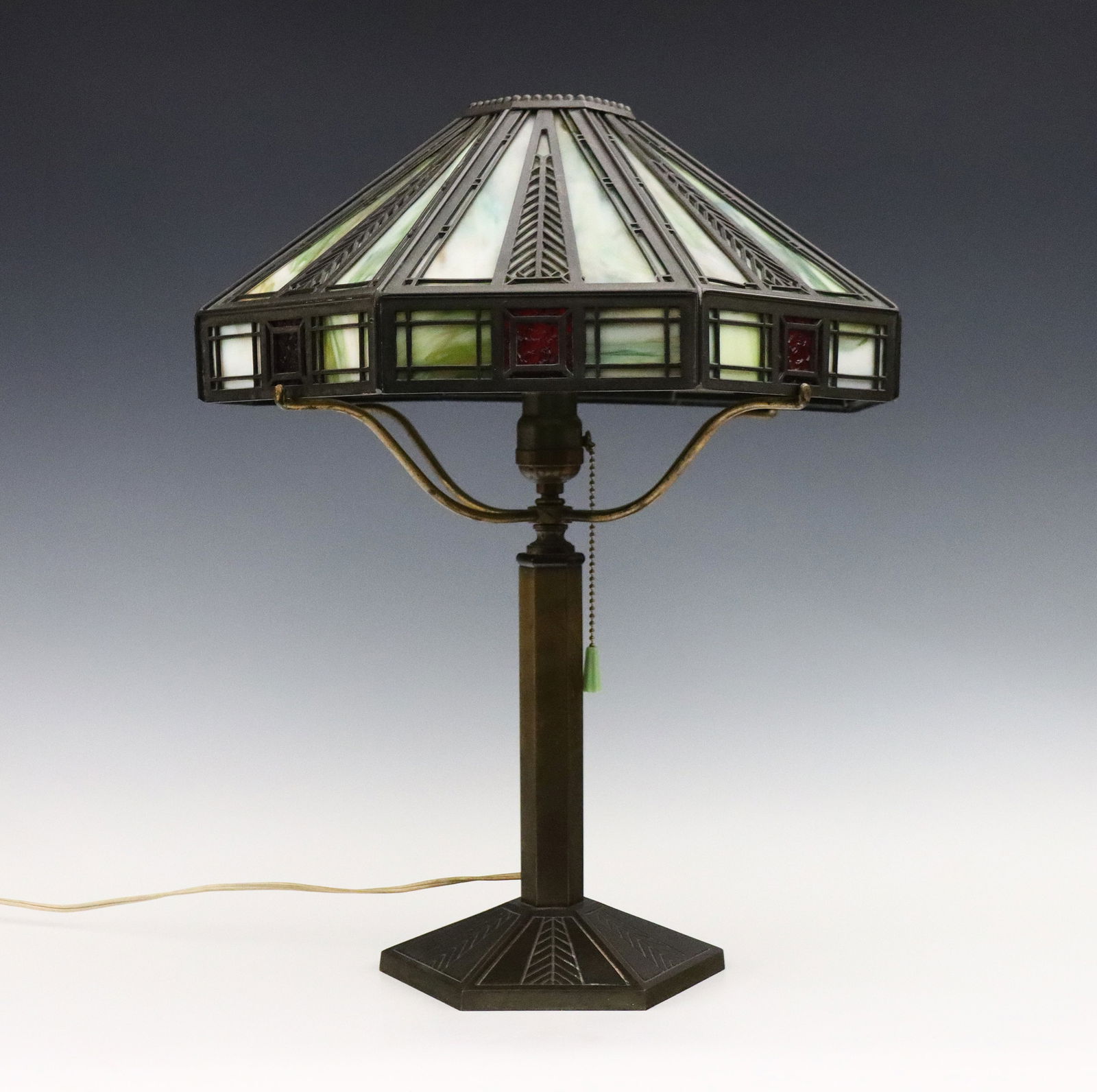 Bradley Hubbard Lamp: An early 20th century Bradley Hubbard table lamp. Cast filigree shade with framed Slag Glass panels in mottled shades of Green, Amber and Ruby on a cast base with matching engraved decoration and hexa