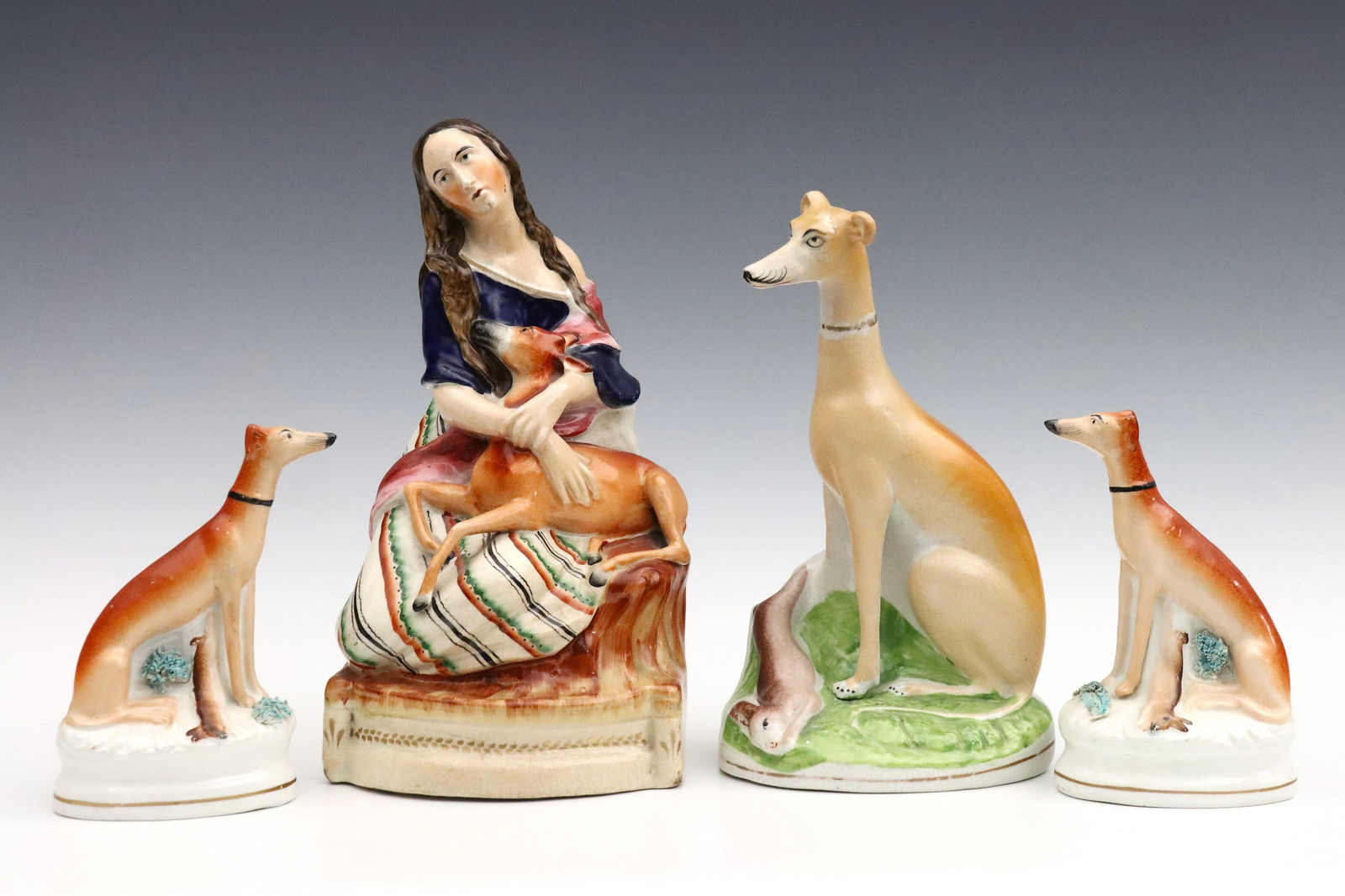 4 Staffordshire Figures: Four late 19th century Staffordshire figures. Includes a figure of a woman cradling a deer, a single Whippet figure of a dog, and a pair of Whippet dogs. Crazing, some surface wear, girl and deer figu