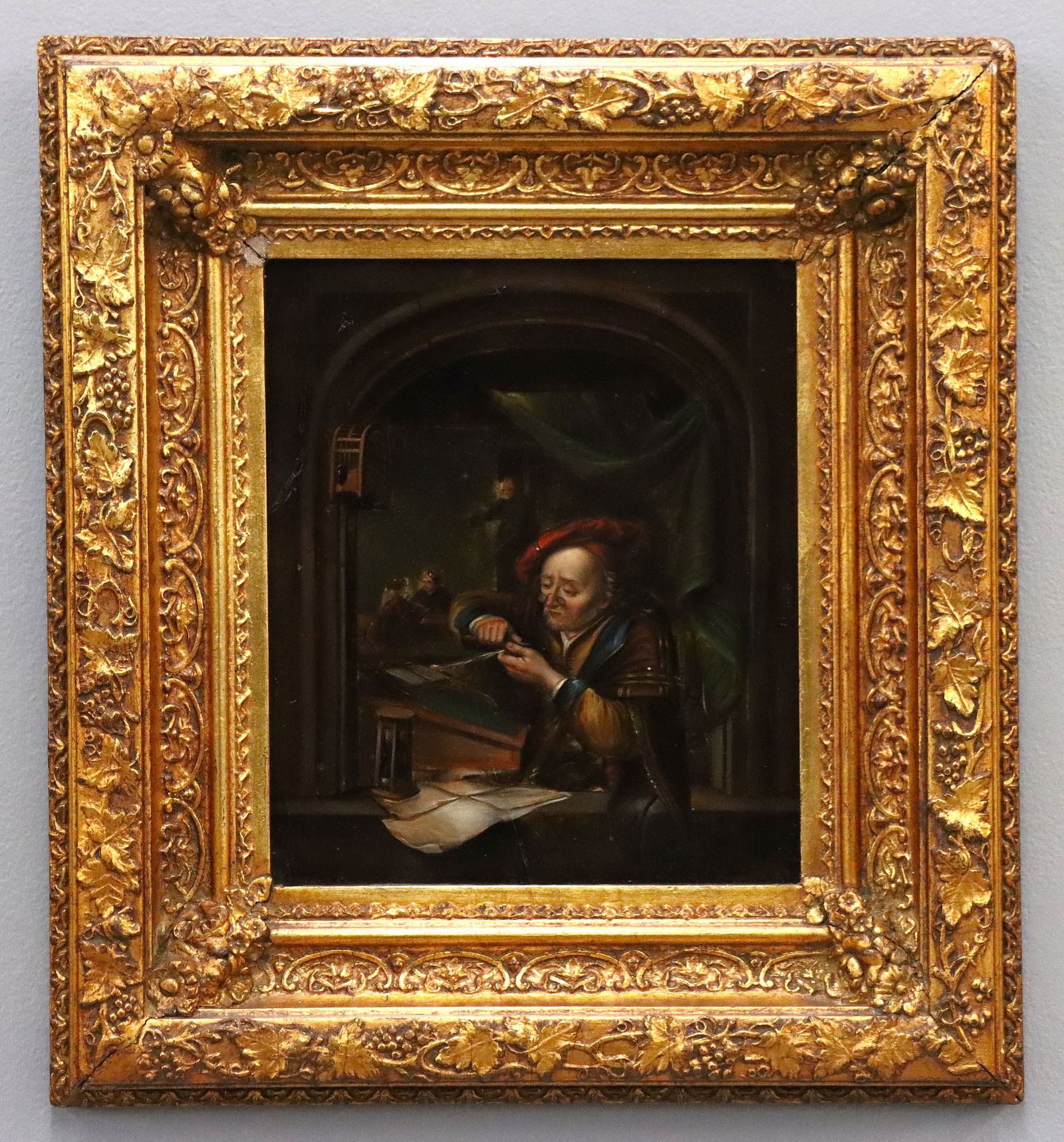 After Gerrit Dou Interior Scene on Tin: A 19th century Dutch oil on tin genre scene after Gerrit Dou (Dutch, 1613-1675). Interior scene after Dou's "The School Master" depicting a schoolmaster seated at a desk set before a window, sharpenin