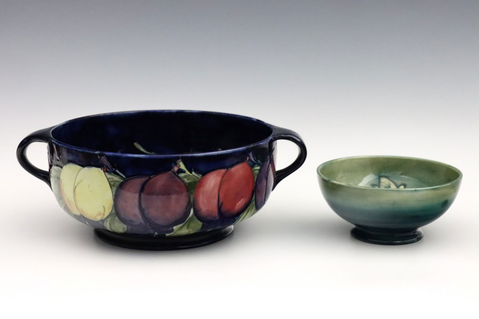 2 Moorcroft Pottery Bowls: Two early to mid 20th century Moorcroft Art Pottery bowls. Includes a handled "Wisteria" pattern bowl and a smaller footed "Hibiscus" pattern bowl. Each with impressed Blue "Moorcroft" and "Made in En