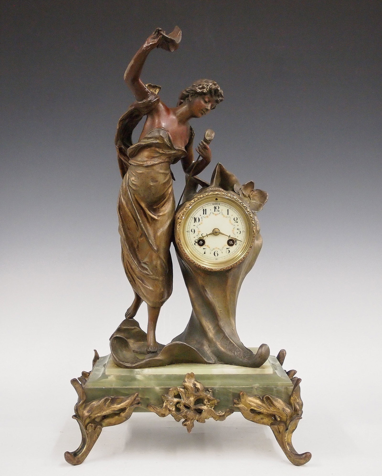 French Art Nouveau Figural Clock: A late 19th century French Art Nouveau figural clock. 8-day time and strike movement with porcelain dial, Arabic numerals and painted floral swags. Two tone Spelter figure entitled "Eaurore" or