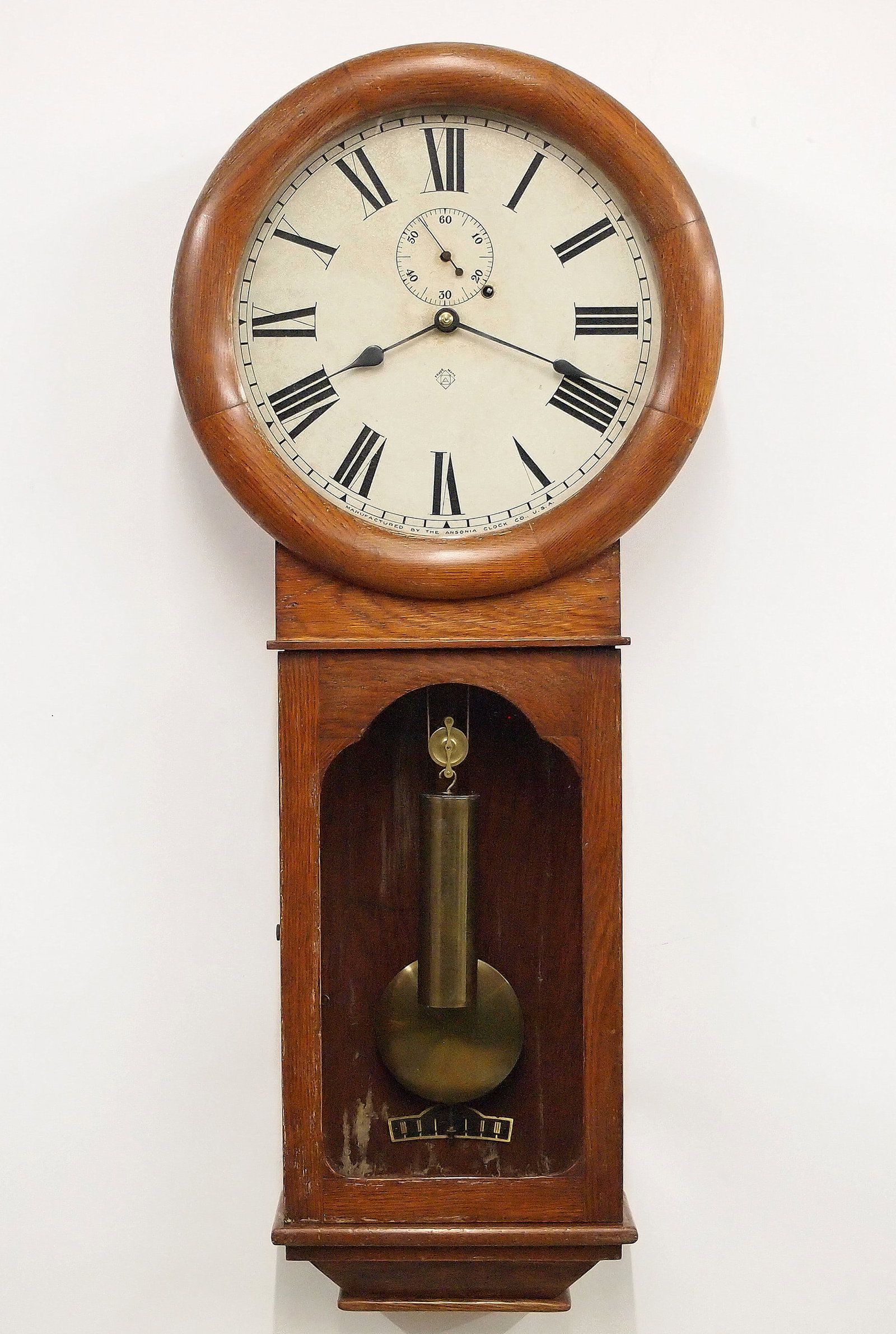Ansonia Standard Regulator Wall Clock: A turn of the century Ansonia Standard Regulator wall clock. 8-day time weight driven only movement with maintaining power, papered metal dial and Roman numerals with subsidiary seconds. Oak case