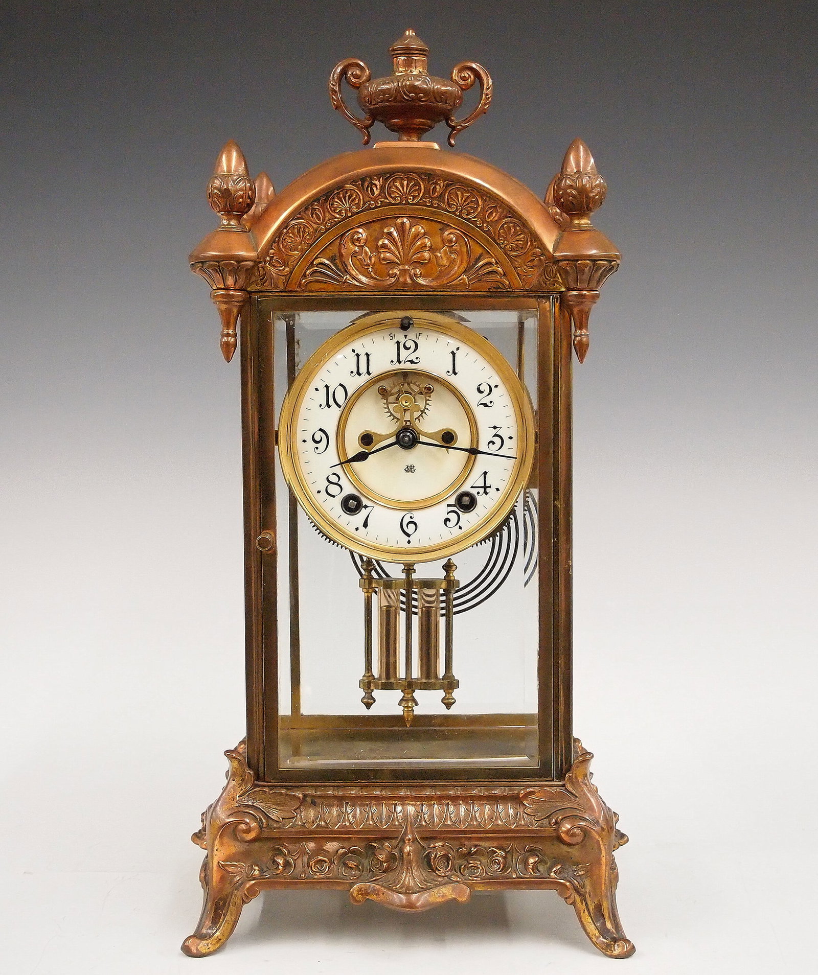 Ansonia Crystal Regulator: A turn of the century Ansonia crystal regulator. 8-day time and strike movement with visible escapement and two-part porcelain dial with Arabic numerals. Spelter case with Copper finish features an