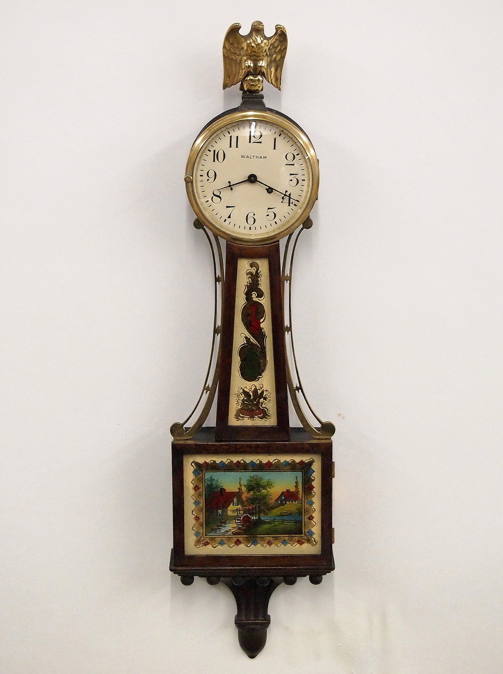 Waltham Mini Banjo Clock: A 1930's miniature Waltham Presentation Banjo clock. 8-day time only movement with lever escapement and painted dial and Arabic numerals. Mahogany case with Brass Eagle finial and side arms,