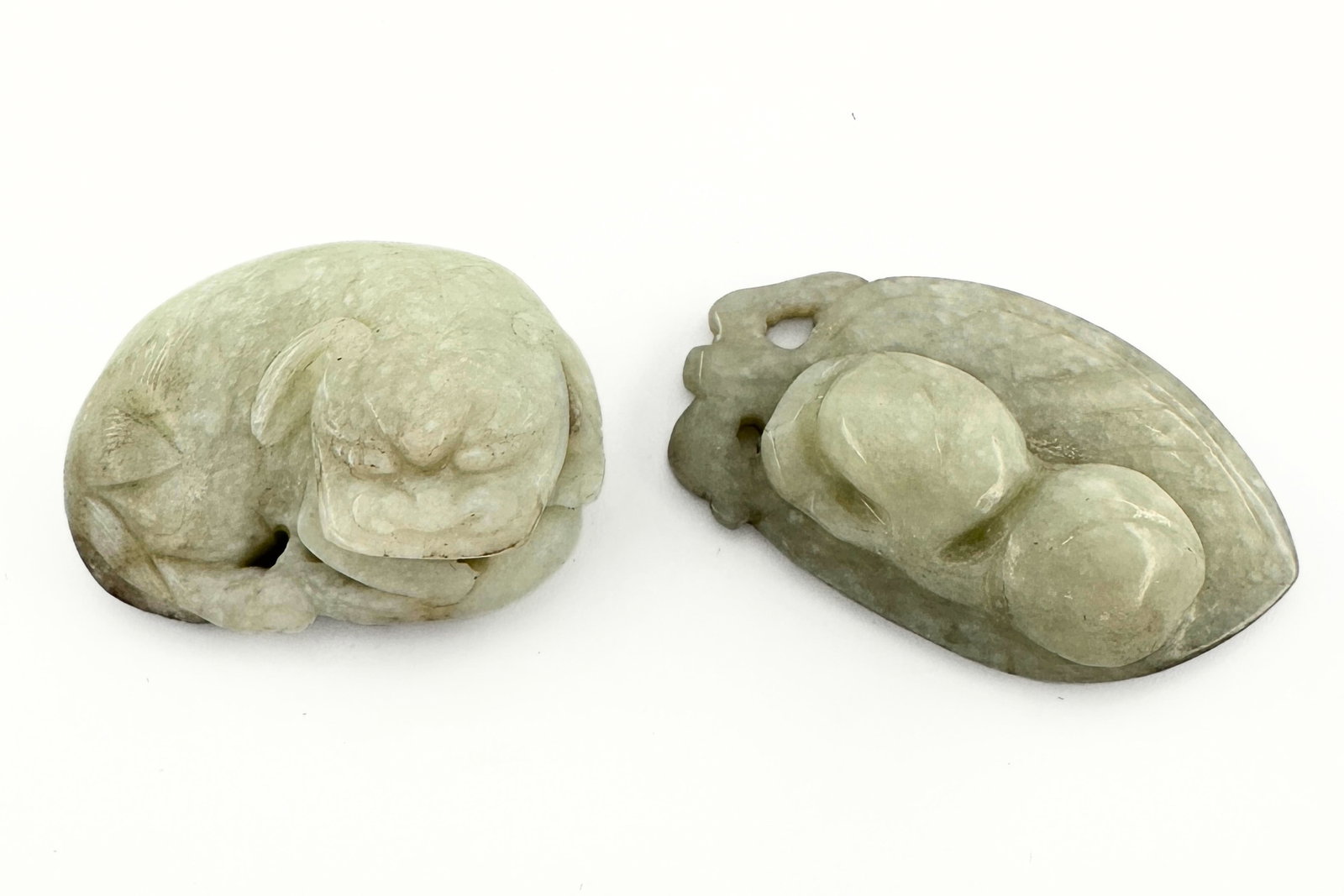 2 Chinese Carved Jade Figures: Two Chinese carved Jade figures. Includes auspicious carvings of a peach and Foo Dog curled around a ball. Surface wear and minor inclusions, small spots of discoloration. Up to 2 3/8" high. ESTIMATE 