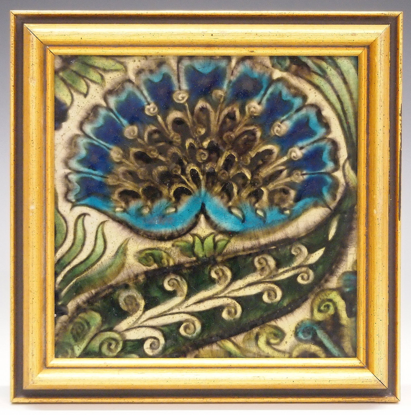 William De Morgan Tile: A late 19th century William De Morgan Art Pottery tile. "Mongolian" pattern tile in shades of Blue and Green, against a creamy White ground. Impressed "D.M. 98" within a circle verso. Crazing, some fl