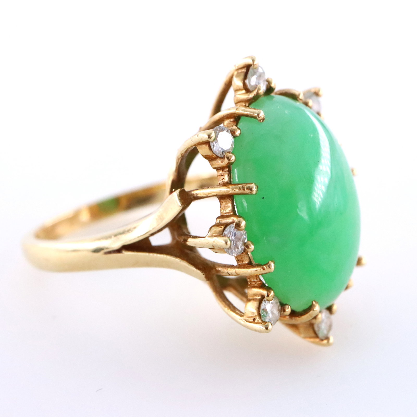 14k Gold, Jade & Diamond Ring: A 14k Gold cocktail ring with Jade and Diamond attributed to Laura Ramsay. Features an oval prong set Jade cabochon, approx. 11.5 mm x 16 mm, surrounded by a halo of round cut prong set Diamond accent