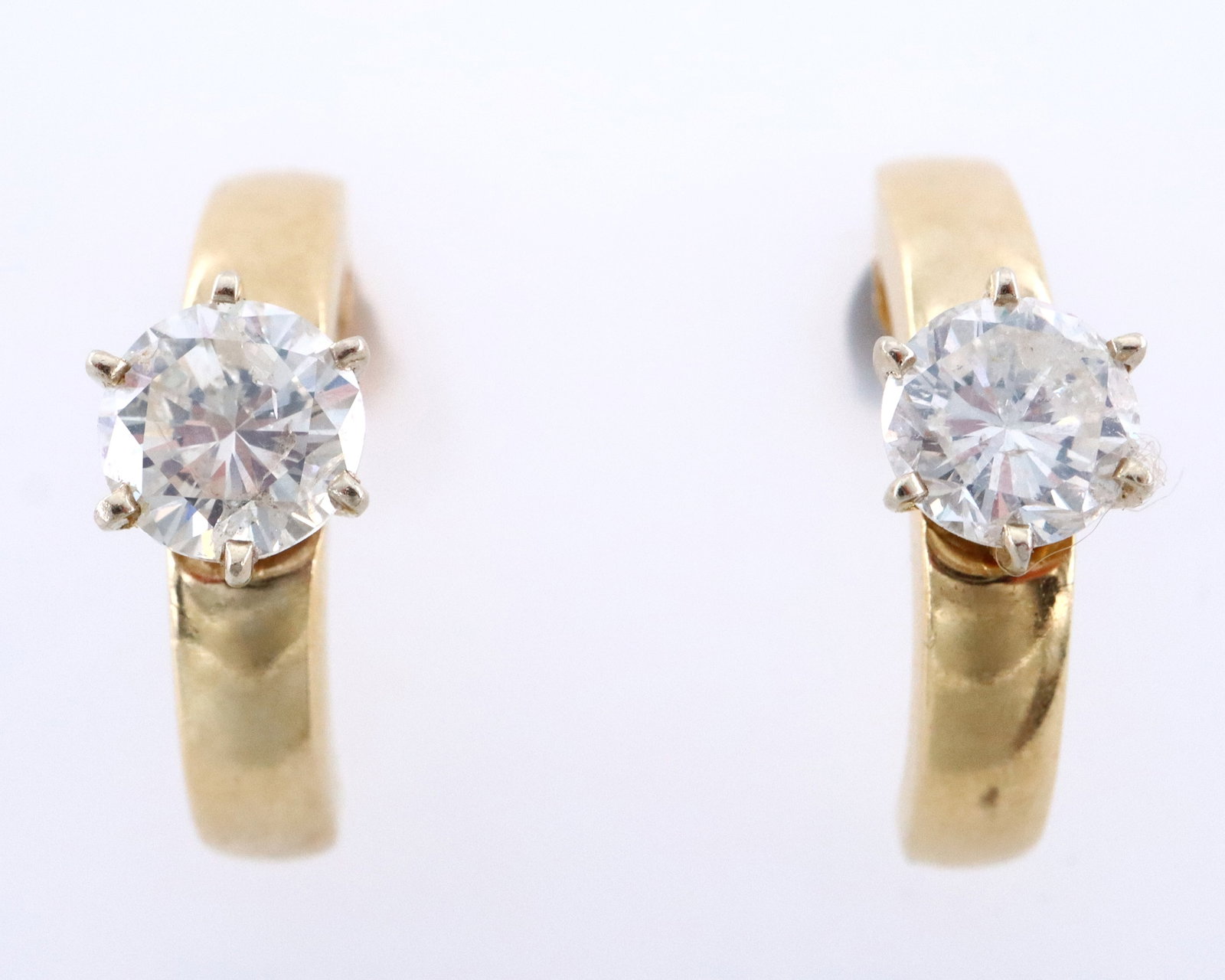 Pr 14k Gold & Diamond Earrings: A pair of 14k Gold and Diamond earrings. Feature a round cut prong set Diamond, approx. 6.5 mm and estimated 1ct each, on half hoop earrings with pierced post backs. Each marked "14k". 5.1 grams total