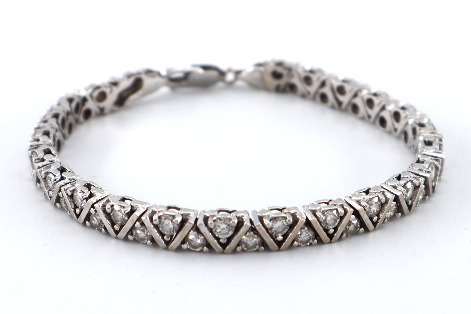14k Gold & Diamond Tennis Bracelet: A 14k White Gold and Diamond tennis bracelet. Features V-form links with forty-five round cut prong set Diamonds, approx. 3 mm each, estimated 4.5 to 5 cttw. Marked "585" at clasp. 21.8 grams total. M