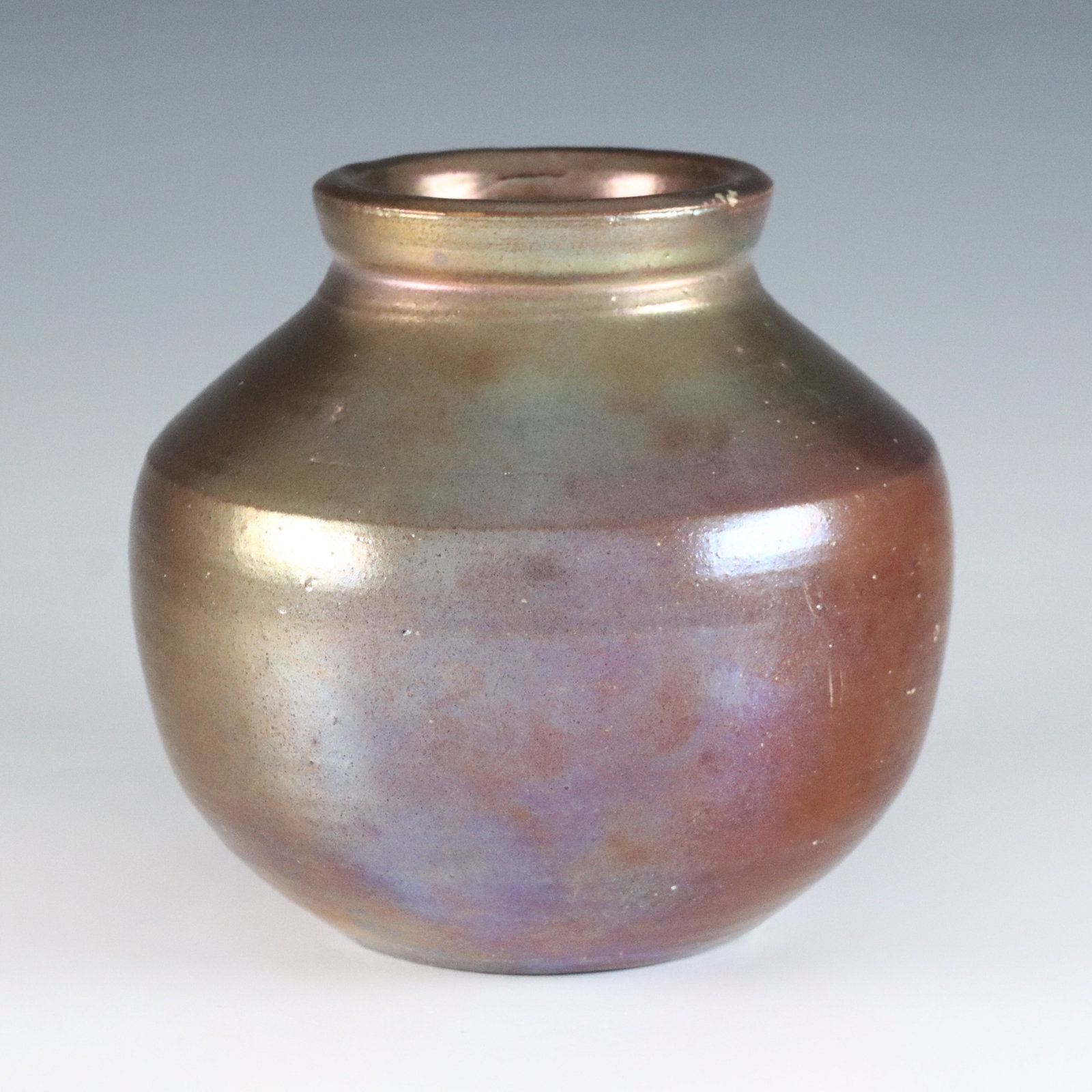 Pewabic Pottery Vase: An early to mid 20th century Pewabic Pottery vase. Bulbous form with iridescent glaze in shades of Oxblood, Copper and Gold. Impressed circular "Pewabic Detroit" mark. Slight surface wear, area with a