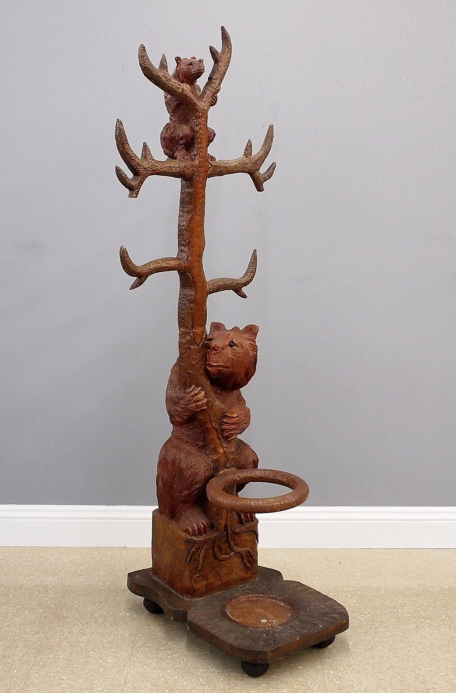 Black Forest Hall Tree: A late 20th century Black Forest style figural hall tree. Carved hardwood construction depicts a mother bear with her cub in the branches of a tree which form the coat hooks over a lower cane rack. So