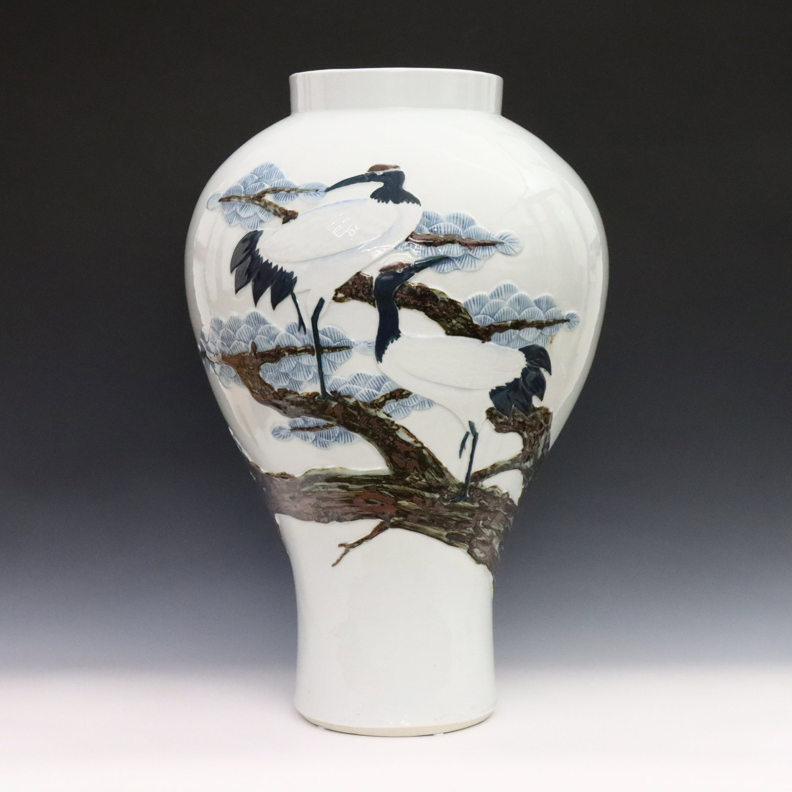 Korean Blue & White Porcelain Vase: A Korean Blue and White porcelain vase. Inverted baluster form decorated with a high relief design of a pair of Cranes perched in pine boughs amidst clouds. Marked at the underside. Minor wear. 25" hi
