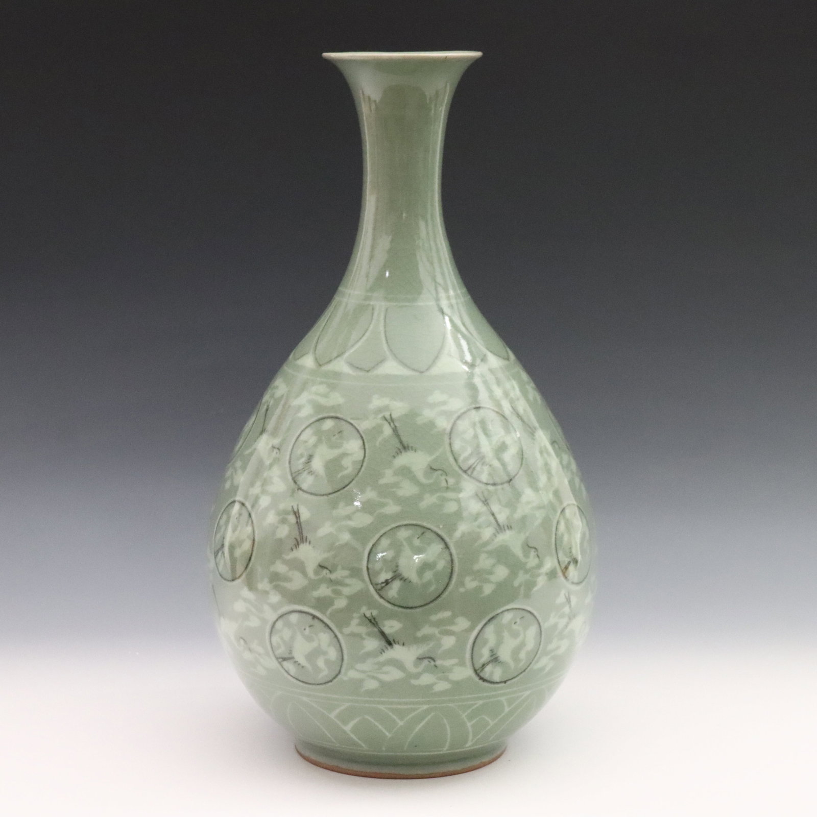 Korean Celadon Porcelain Vase: A Korean Goryeo-style Celadon porcelain vase. Bottle form with a flared rim, decorated with cranes, clouds, and medallions below a lotus leaf band in a crackle glaze. Marked at the underside. Repair a