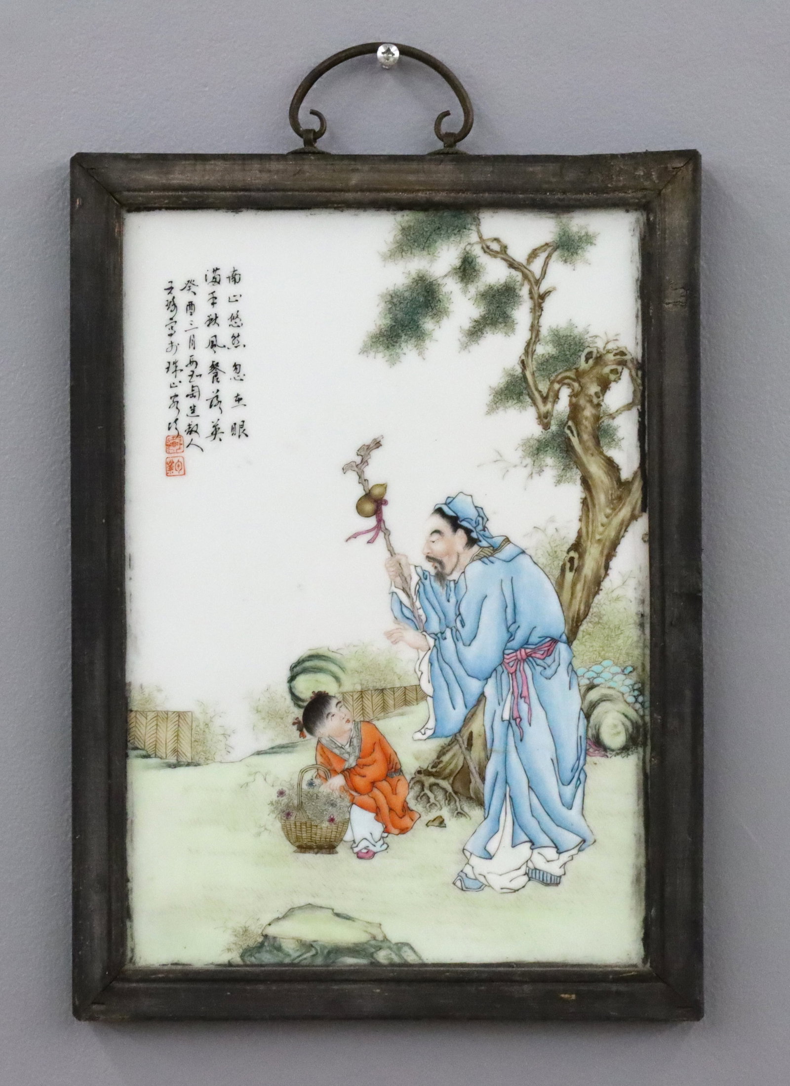 Chinese Porcelain Plaque: An early 20th century Chinese porcelain plaque. Polychrome enameled decoration depicting a Scholar next to a child with a flower basket. Calligraphy and Red seals upper left. Minor wear, Black paint t