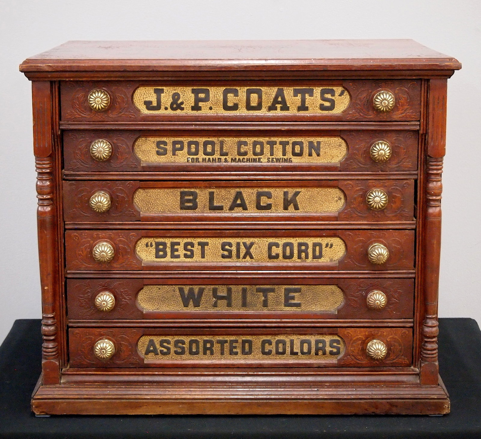 J. & P. Coats Spool Cabinet: A turn of the century J. & P. Coats Spool Cabinet. Walnut construction features six labeled dovetailed drawers with brass knobs flanked by pilasters at either side along with an advertising panel