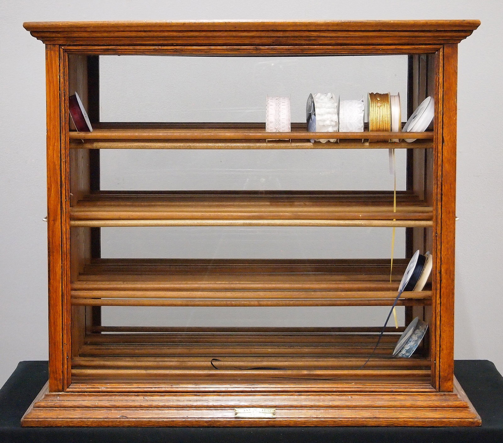 A.N. Russell & Sons Ribbon Cabinet: A turn of the century A.N. Russell & Sons Ribbon Cabinet. Oak construction with glass front and back that features four vertical pull out racks, each with four shelves. Brass plaque at the base that