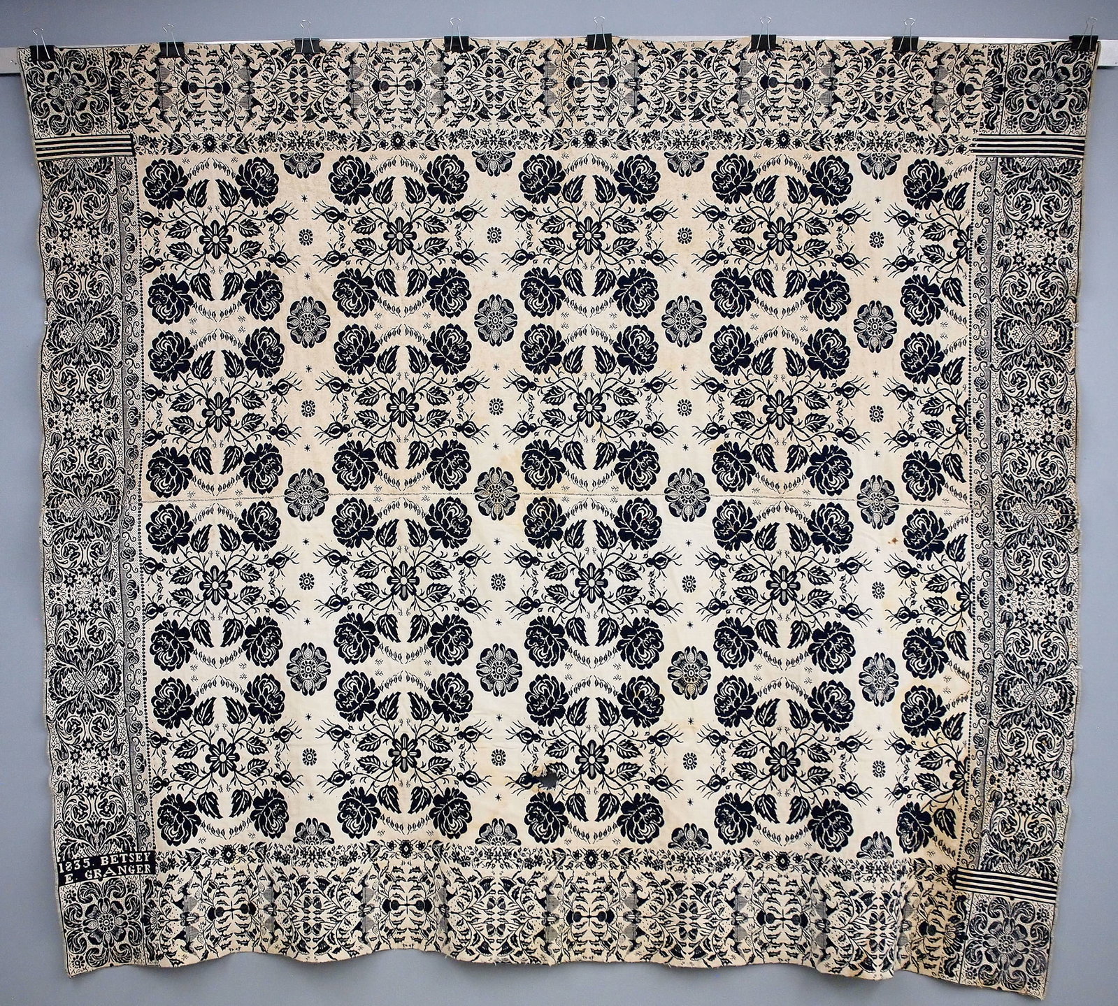 American Jacquard Coverlet: An early 19th century American Jacquard coverlet. Two piece construction in Navy Blue and White with a repetitive pattern of medallions, lilies and trumpet flowers contained within alternating borders