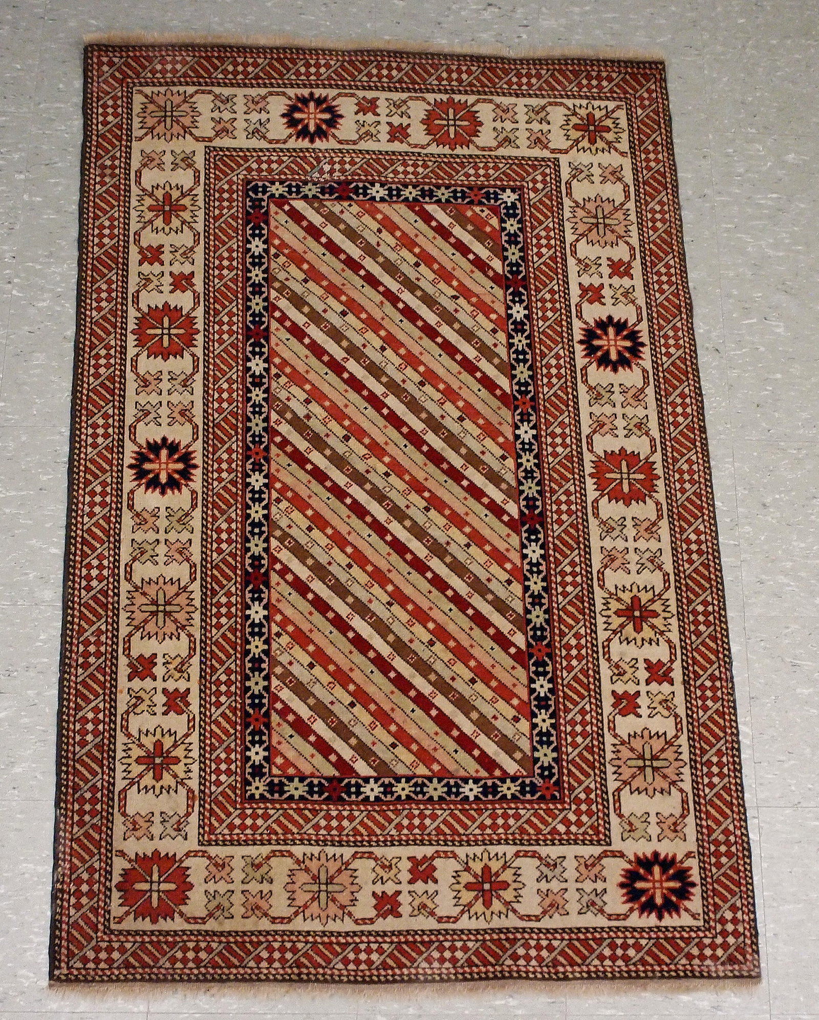 Persian Hamadan Rug: A 3' 5" x 5' 3" Persian Hamadan Rug. Featuring linear and geometric motifs in shades of Red, Pink, Navy Blue, Sage Green, and Cream. Light wear, some losses and staining. ESTIMATE $200-300