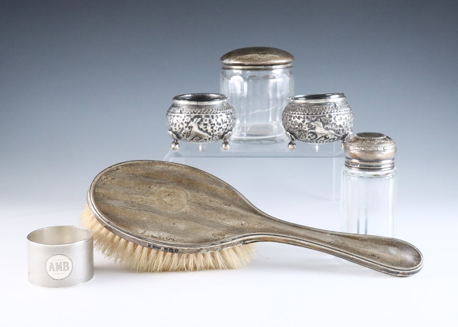 6 Sterling Items: Six 20th century Sterling Silver items. Includes a pair of salt cellars, likely Indian, two English glass jars with Sterling lids, an English Sterling hairbrush and napkin ring. Salt cellars unmarked,