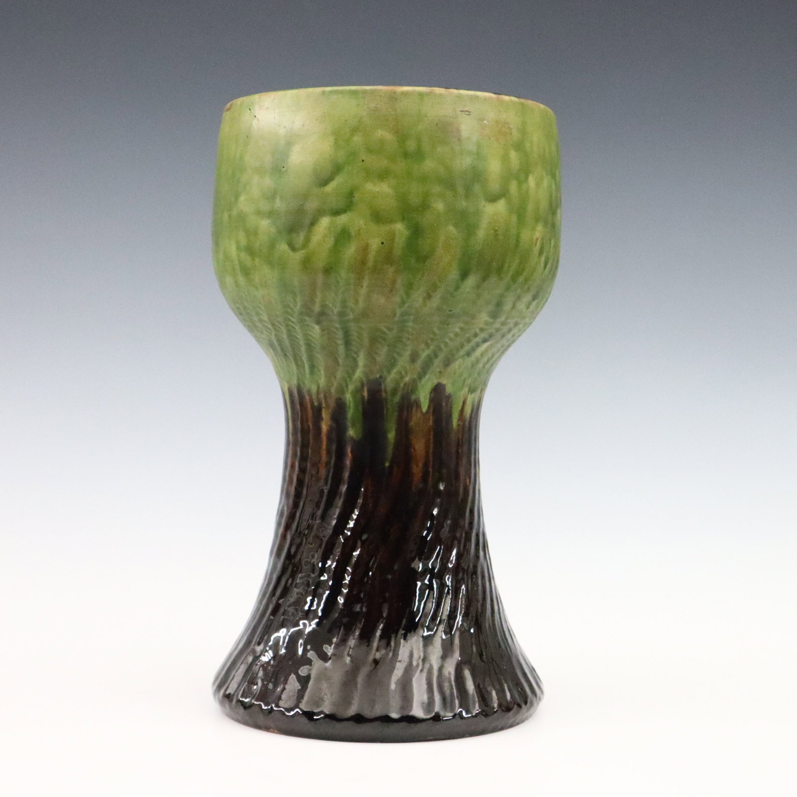Herman Kahler Art Pottery Vase: A turn of the century Herman Kahler Art Pottery vase. Chalice form with textured body and multi-color drip glaze. Incised "HAK" monogram with partial paper retailer's label. Minor wear. 11 1/4" high. 