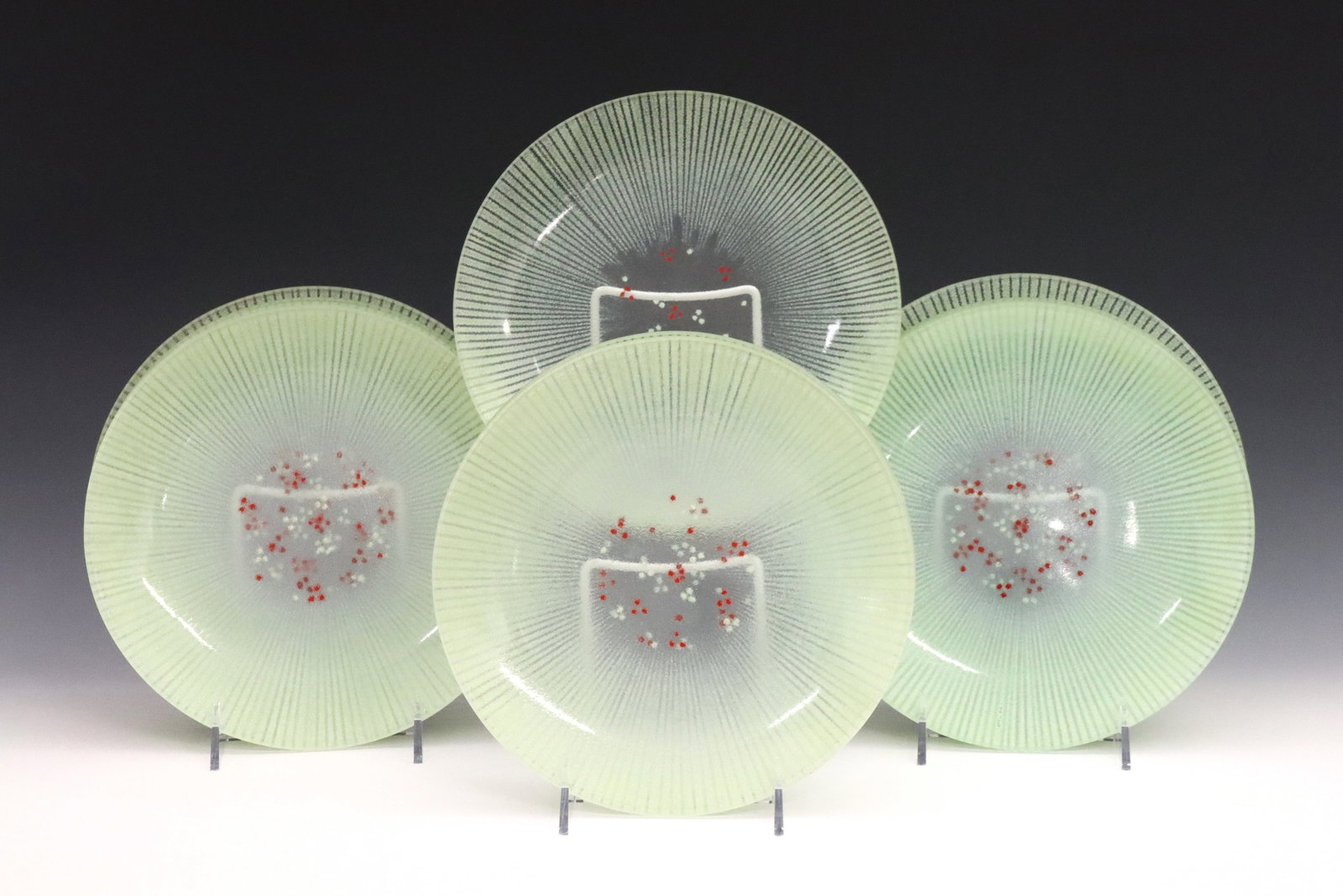 11 Maurice Heaton Plates: Eleven Mid Mod enameled glass plates by Maurice Heaton (Swiss/American, 1900-1990). Enameled Mint Green pattern at the border with Mint Green/Red dot design at the well. Each marked "M.H.". Very minor
