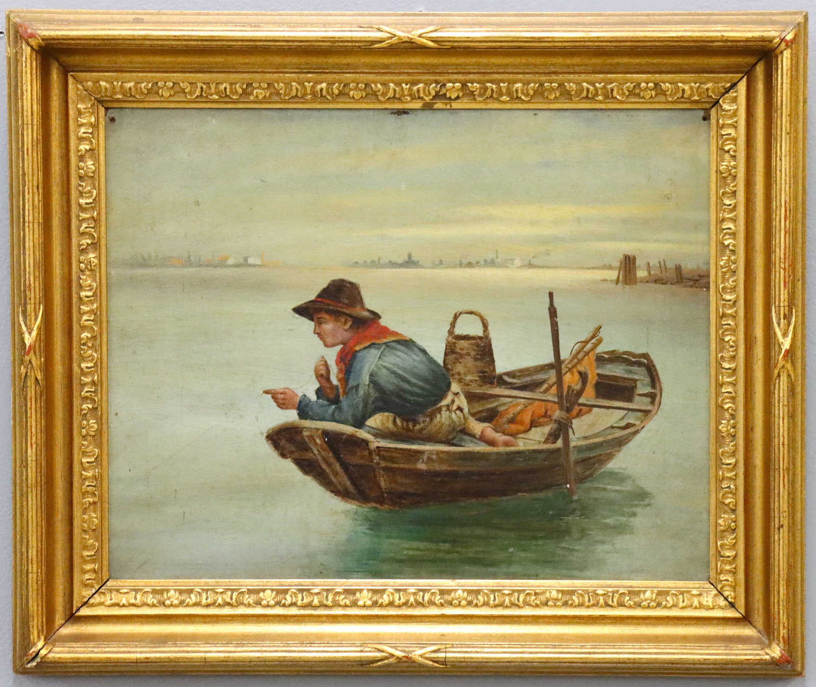 European Fishing Scene: A turn of the century European oil on board fishing scene. Depicts a young man fishing with a hand line and a basket for his catch on his boat. Unsigned. Three holes/losses along the top of the image,